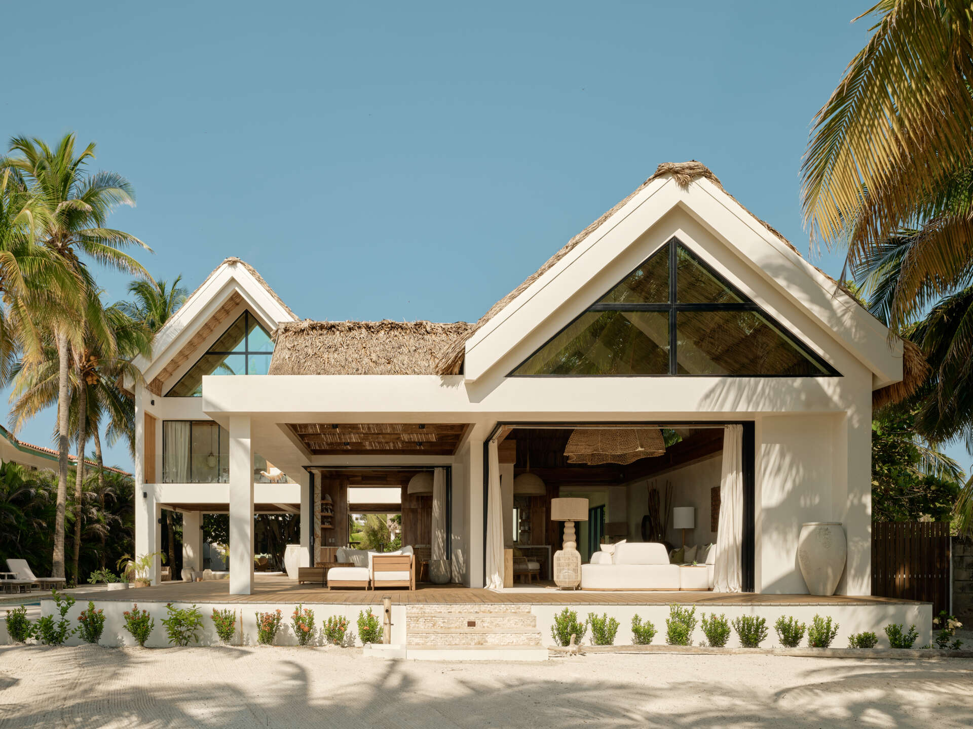 A calm arrival sequence shaped by wood, plaster, and filtered light, guiding visitors from lush planting toward the heart of the home.