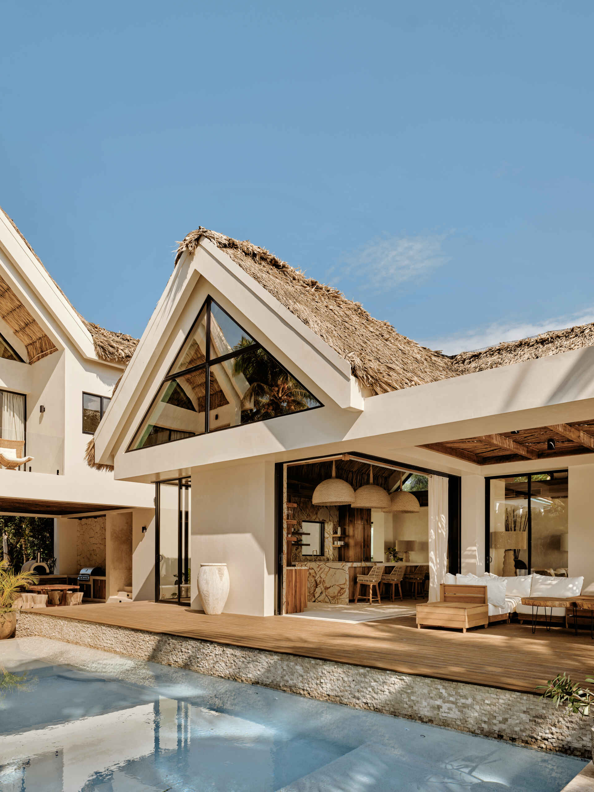 A calm arrival sequence shaped by wood, plaster, and filtered light, guiding visitors from lush planting toward the heart of the home.