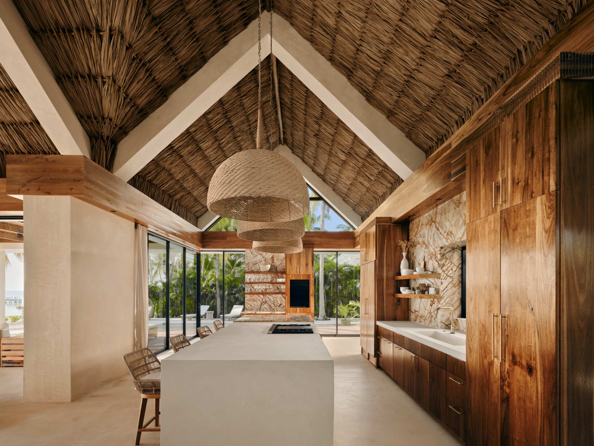 The kitchen is positioned as part of the main living zone, supporting daily use as well as larger gatherings. Its location keeps it visually and physically connected to the outdoor areas. White concrete countertops and local Sam wood cabinetry balance durability with warmth, while custom reeded detailing adds texture to the space.
