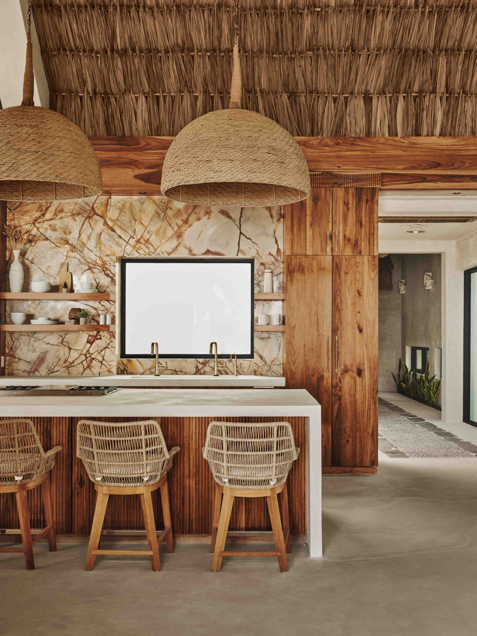 The kitchen is positioned as part of the main living zone, supporting daily use as well as larger gatherings. Its location keeps it visually and physically connected to the outdoor areas. White concrete countertops and local Sam wood cabinetry balance durability with warmth, while custom reeded detailing adds texture to the space.