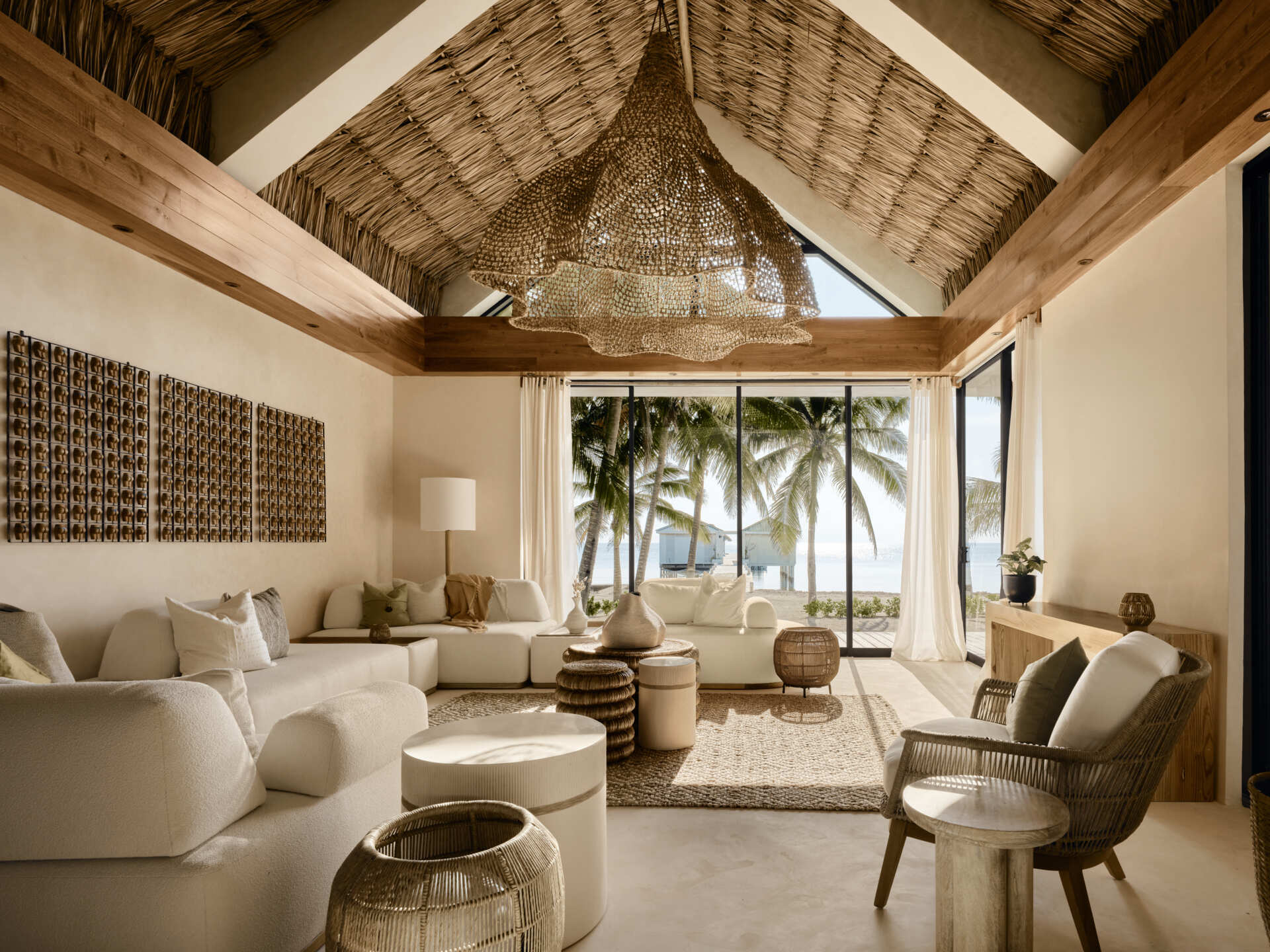 The living room was designed to dissolve the boundary between inside and outside. Large pocketing doors slide fully open, allowing ocean breezes to pass through the space and connect it directly to the pool and patios.