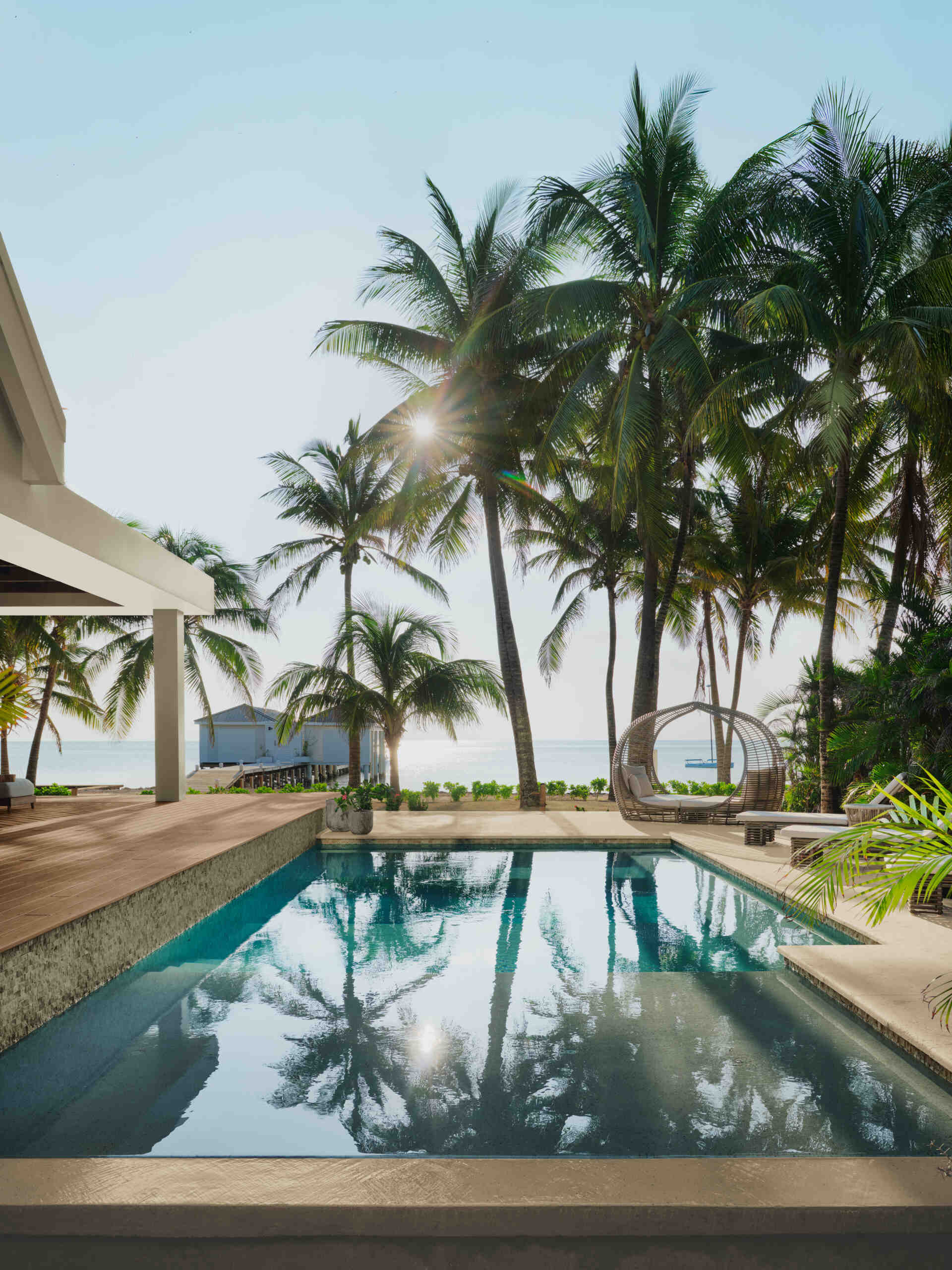 The pool anchors the main living areas and acts as a visual and social connector between the structures. It sits just beyond the living room, reinforcing the idea that outdoor spaces are part of everyday life. Movement between swimming, dining, and lounging happens without separation, keeping everyone within view.