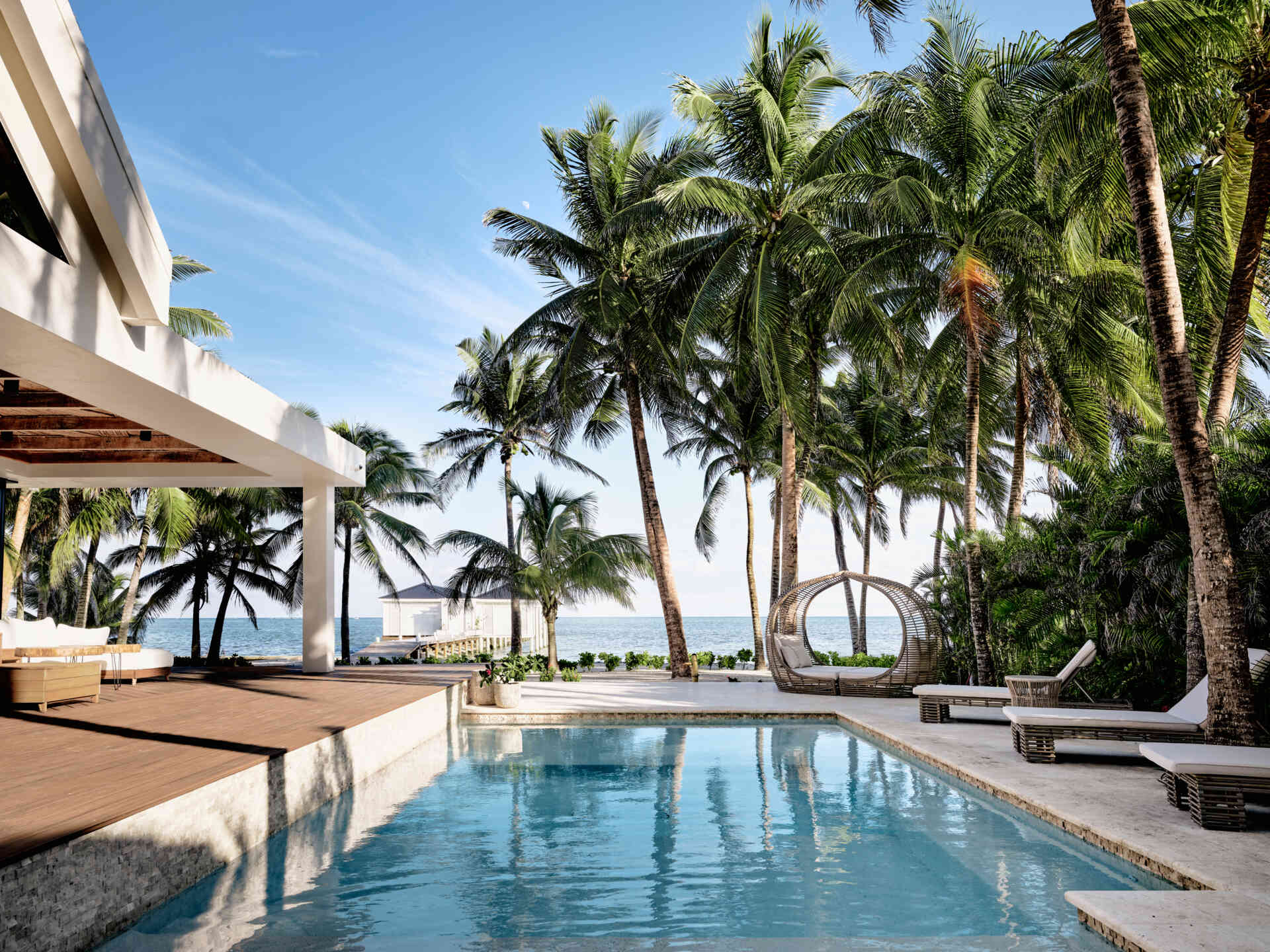 The pool anchors the main living areas and acts as a visual and social connector between the structures. It sits just beyond the living room, reinforcing the idea that outdoor spaces are part of everyday life. Movement between swimming, dining, and lounging happens without separation, keeping everyone within view.