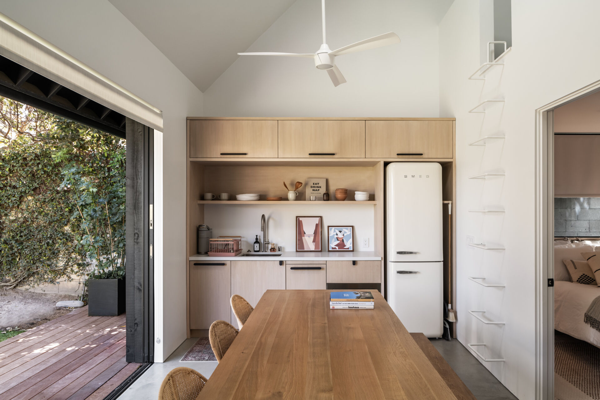 Inside this modern ADU, the material palette mirrors the main house, creating visual continuity across the site. The living and dining areas are compact yet complete, offering independence without feeling isolated, while the kitchenette lines the wall.