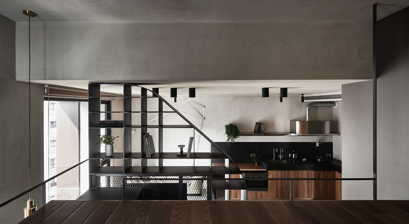 The mezzanine in this tiny apartment houses the bedroom, featuring a loft bed that maximizes vertical space. Beside the bed, another pegboard wall mirrors the one downstairs, creating a visual connection between levels. Behind the bed, a custom-built open closet with integrated lighting provides storage without crowding the space.