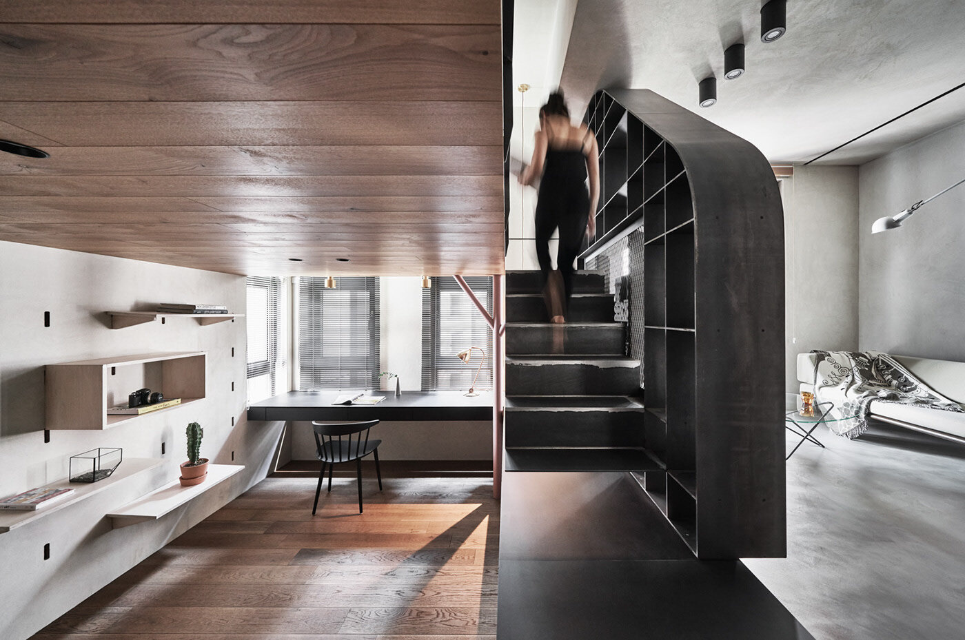 Steel stairs in a tiny apartment connect three levels while enhancing visual flow and spatial efficiency.