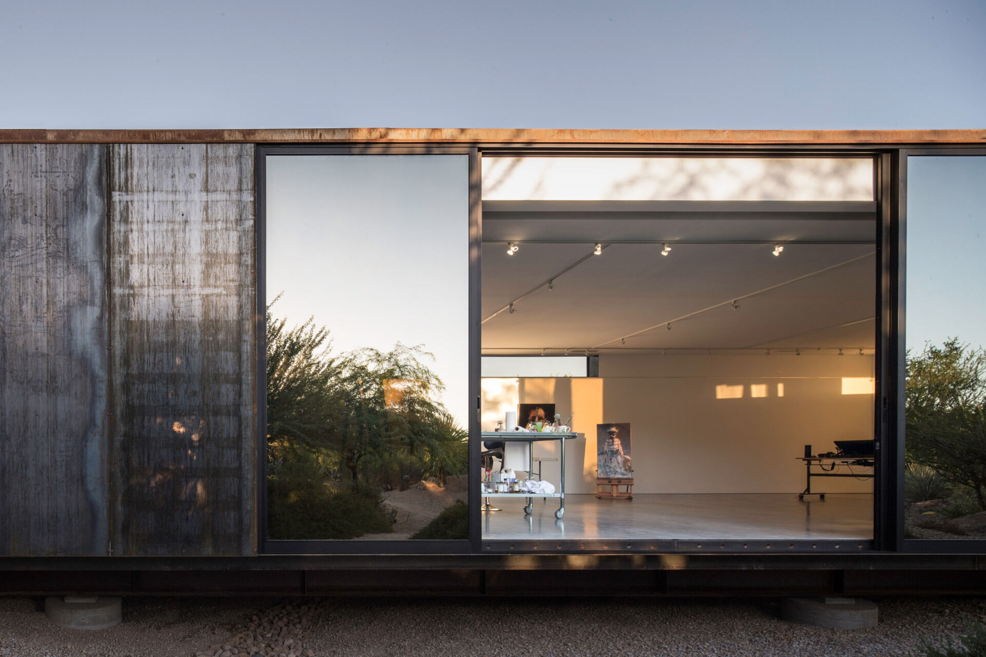 Reflective glazing and standard steel panels help this desert studio balance efficiency, performance, and visual restraint.