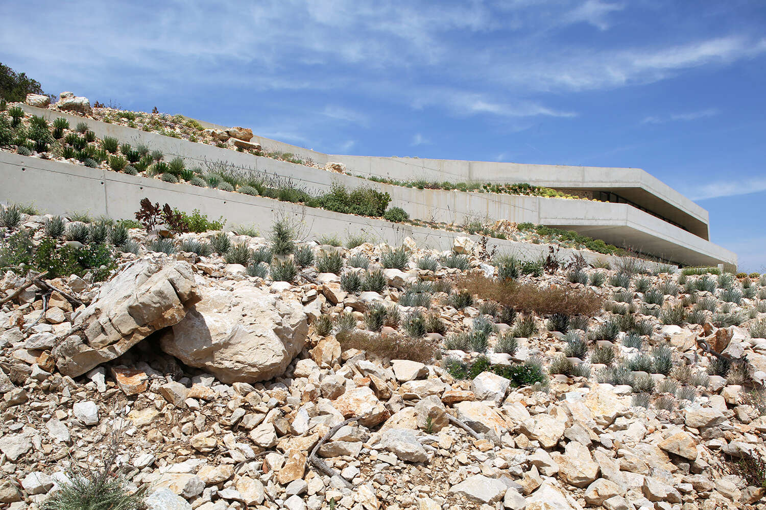Esta casa en la ladera forma una zona residencial entre los muros y está inspirada en los refugios originales excavados en el terreno.