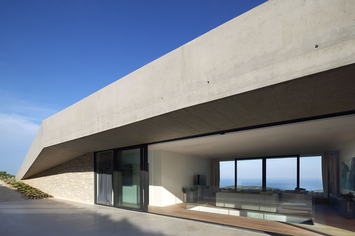 El salón del primer piso está sombreado por un profundo voladizo de concreto, creando sombra y comodidad pasiva.