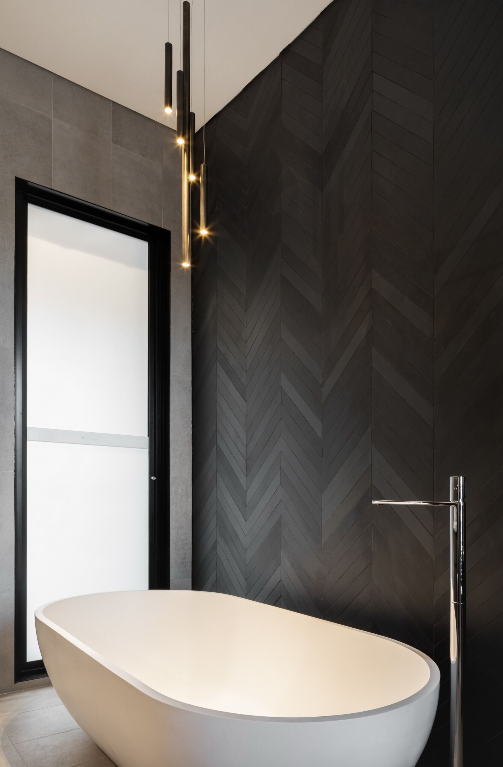 Chevron tiles and garden facing windows give this modern bathroom a calm, private feel.