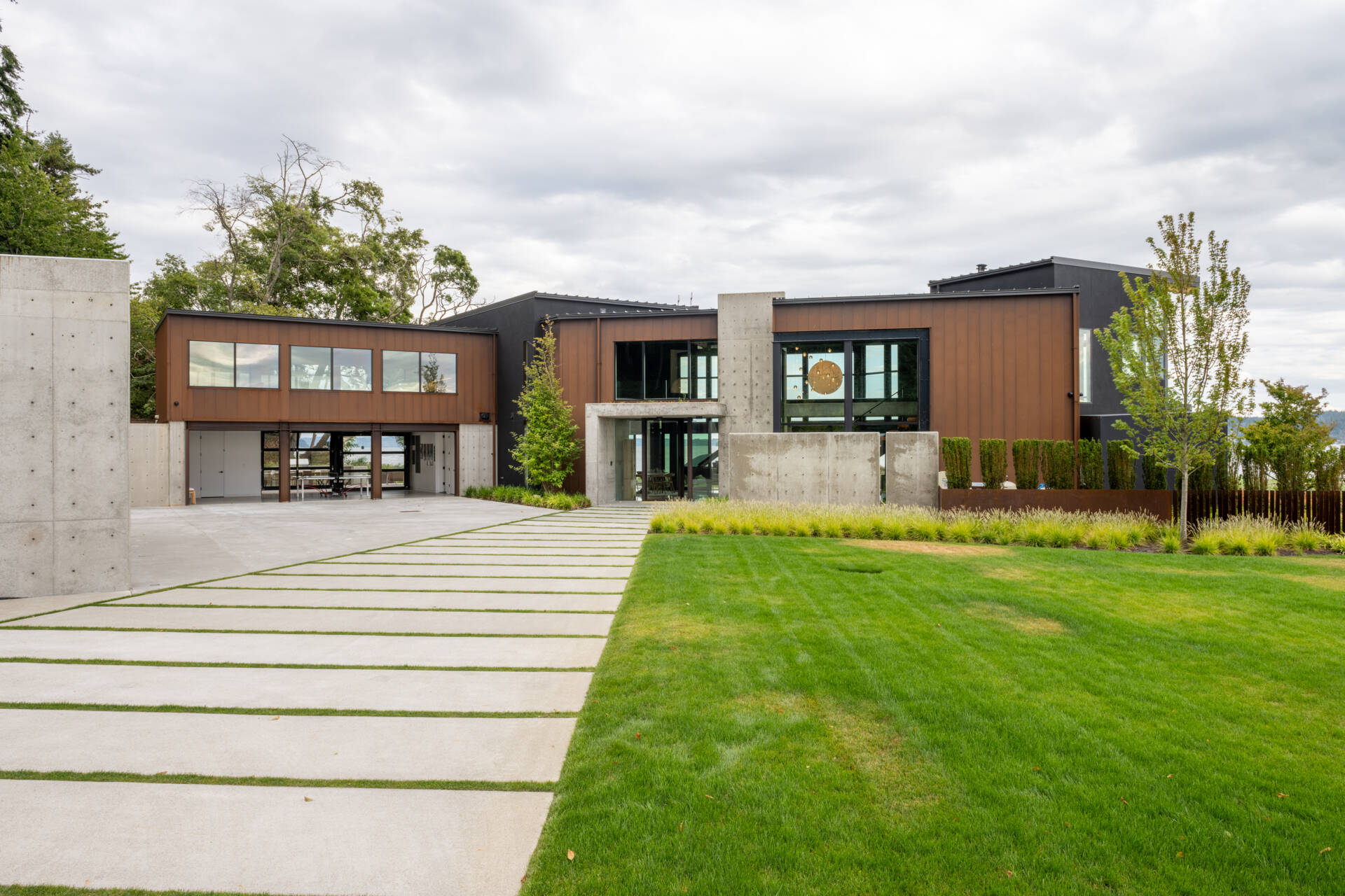A steep hillside behind the home shaped how access and structure were planned. The driveway and garage zones are engineered as protective elements rather than simple arrival points.