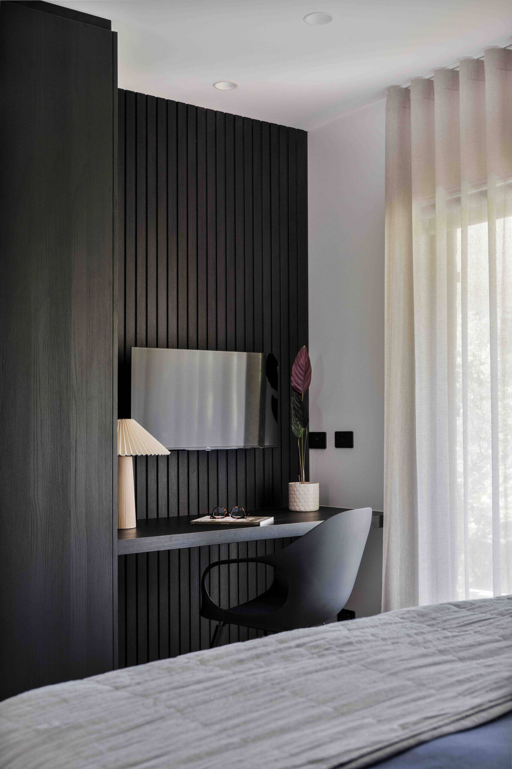 This primary bedroom mirrors the hotel like quality the homeowners dreamed of. A king bed sits against the same Ravenswood black wall panel seen throughout the home, giving the room visual continuity. Soft window treatments, a dedicated study nook and three walls of robes create a generous and refined retreat.