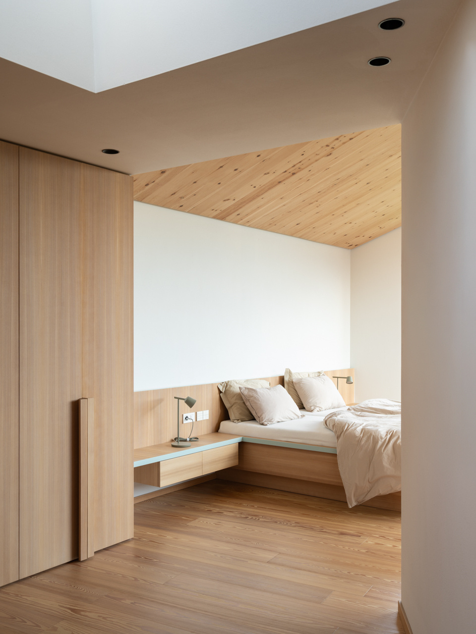 Skylit bedrooms use wood, and simple details to create calm private spaces above the valley.