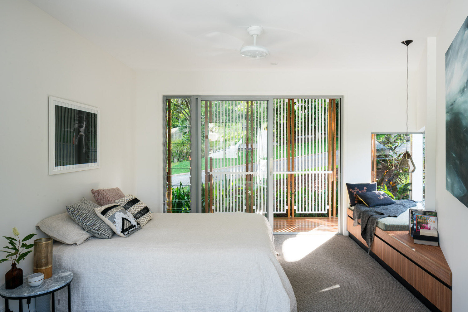 A built-in window seat and private outdoor space make the main bedroom feel calm and connected to the garden.