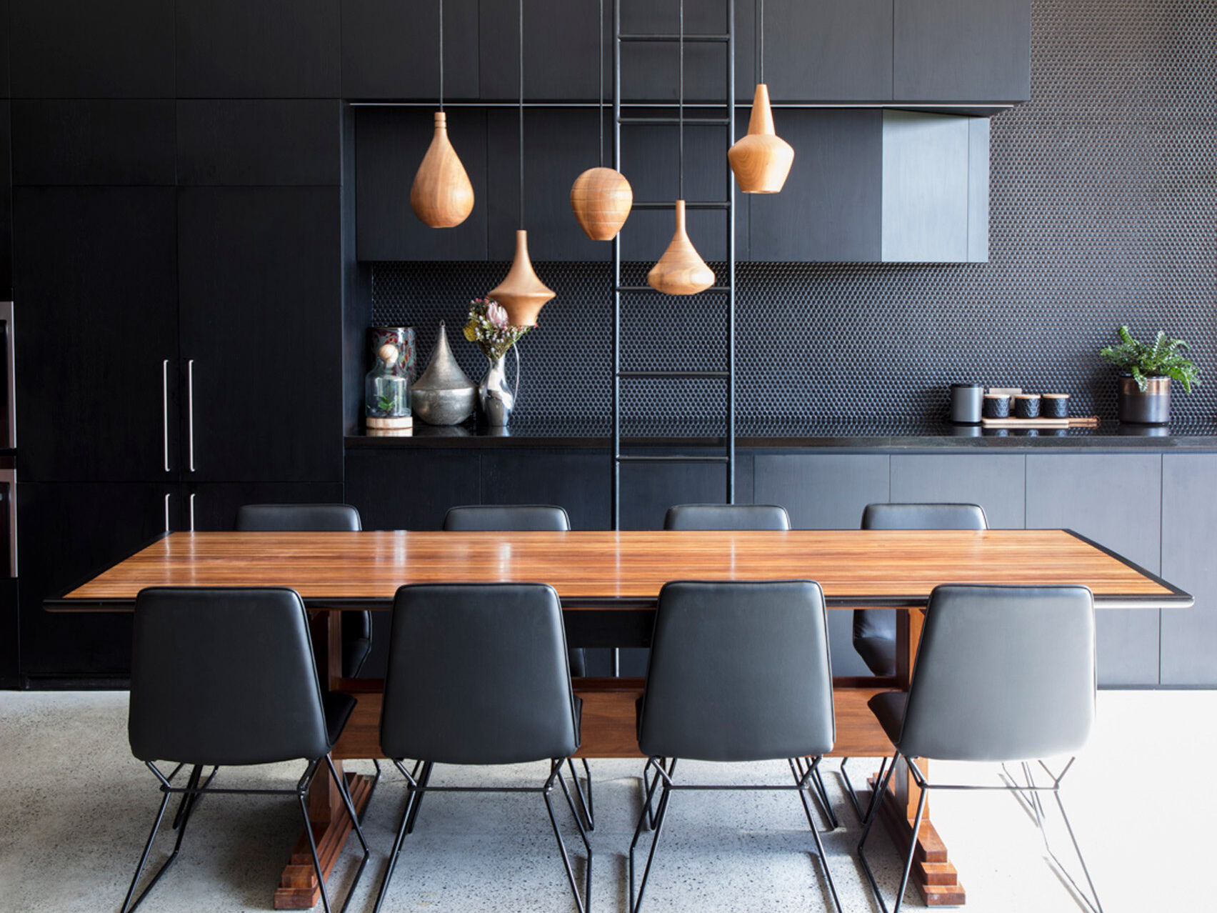 Tall cabinetry pairs with a simple ladder and warm wood pendant lights that highlight the dining space beautifully.
