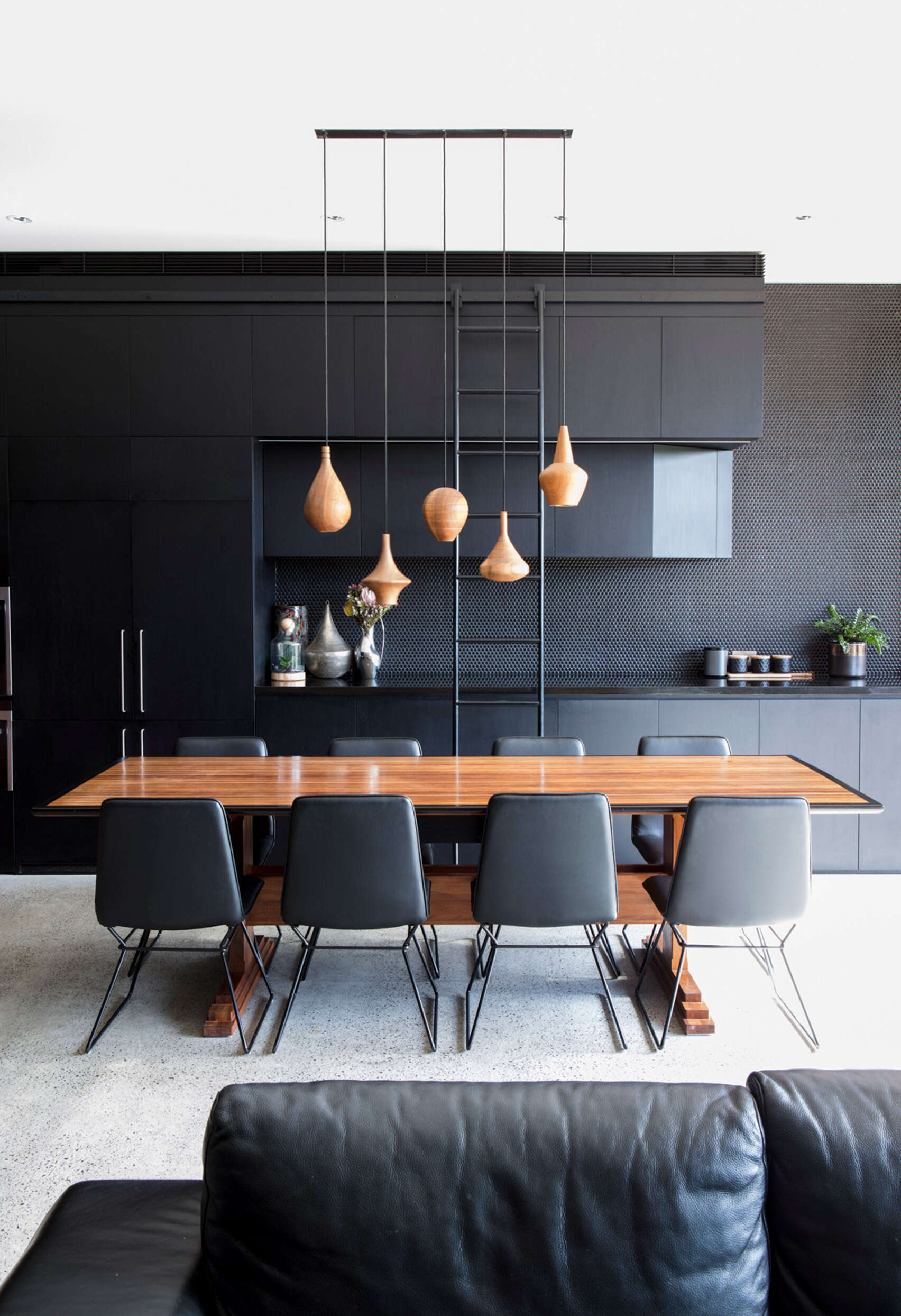 Tall cabinetry pairs with a simple ladder and warm wood pendant lights that highlight the dining space beautifully.