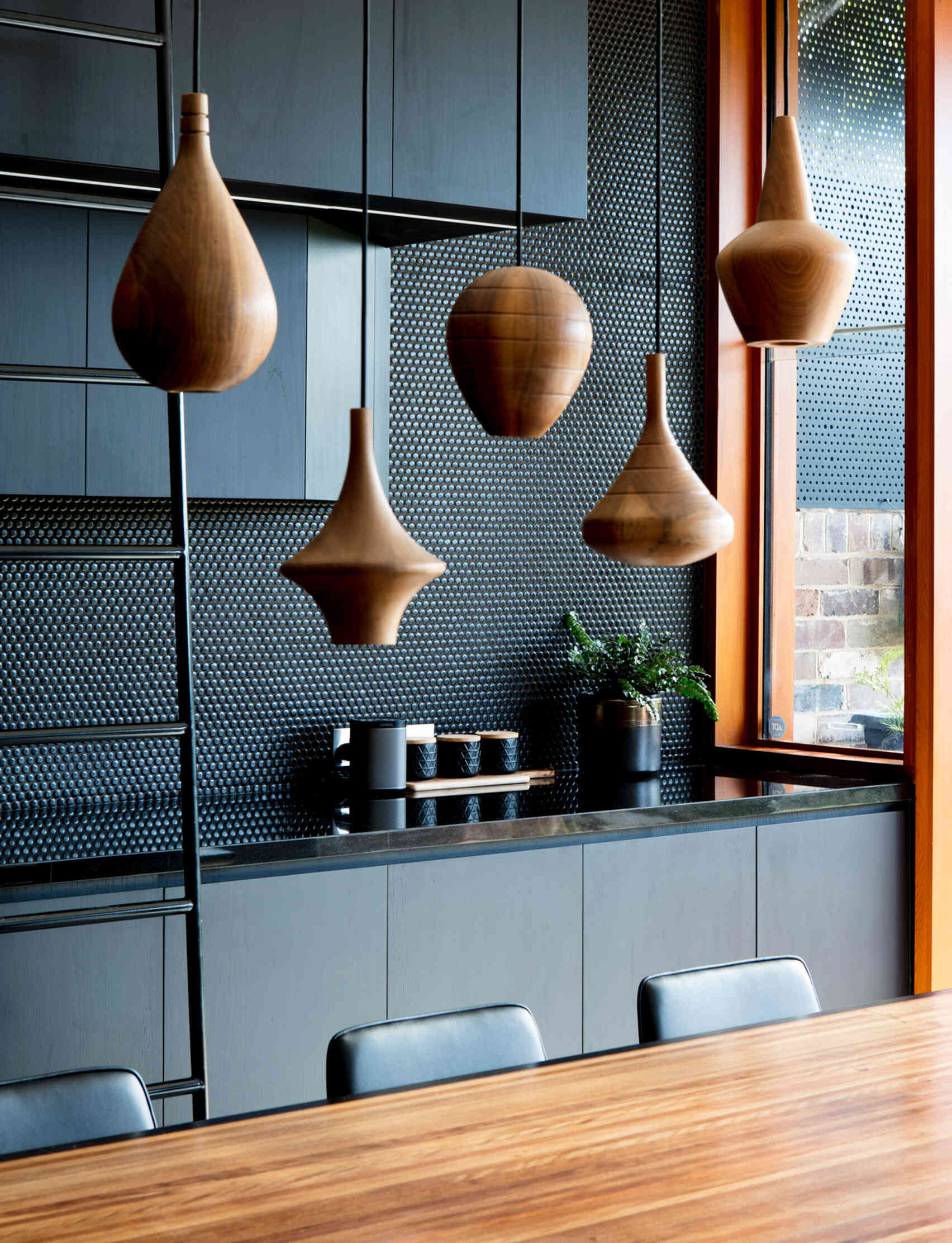 Tall cabinetry pairs with a simple ladder and warm wood pendant lights that highlight the dining space beautifully.
