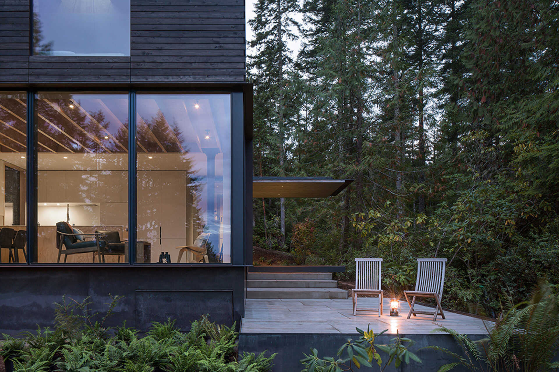 A modern cabin with a patio and covered porch that offers outdoor living in any weather.
