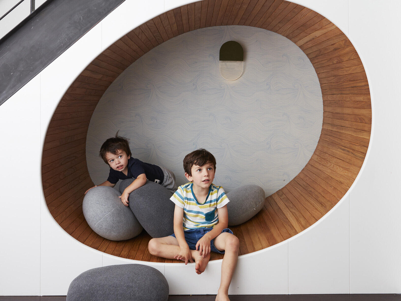 A curved, wood lined seating nook tucked under the stairs turns unused space into a standout feature.