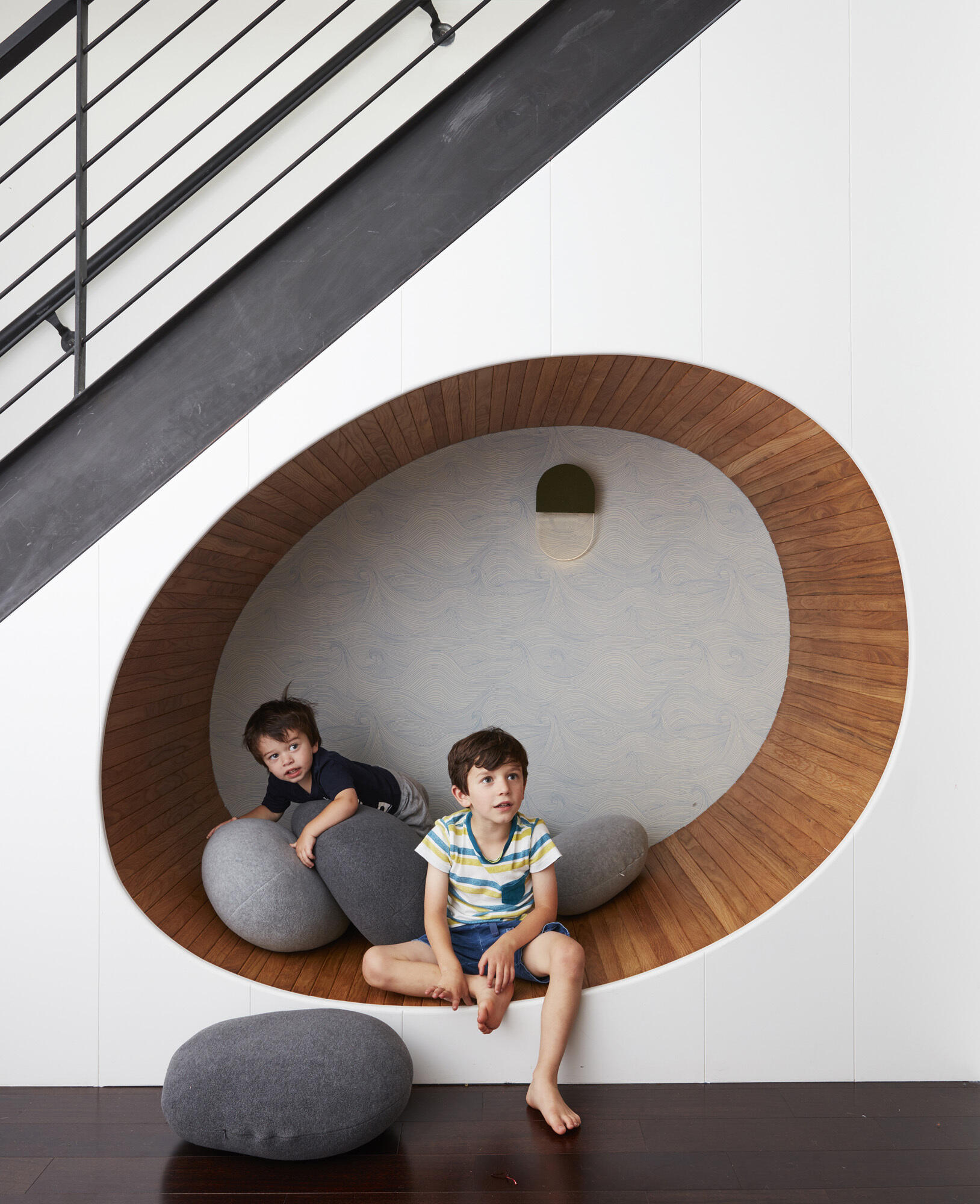 A curved, wood lined seating nook tucked under the stairs turns unused space into a standout feature.