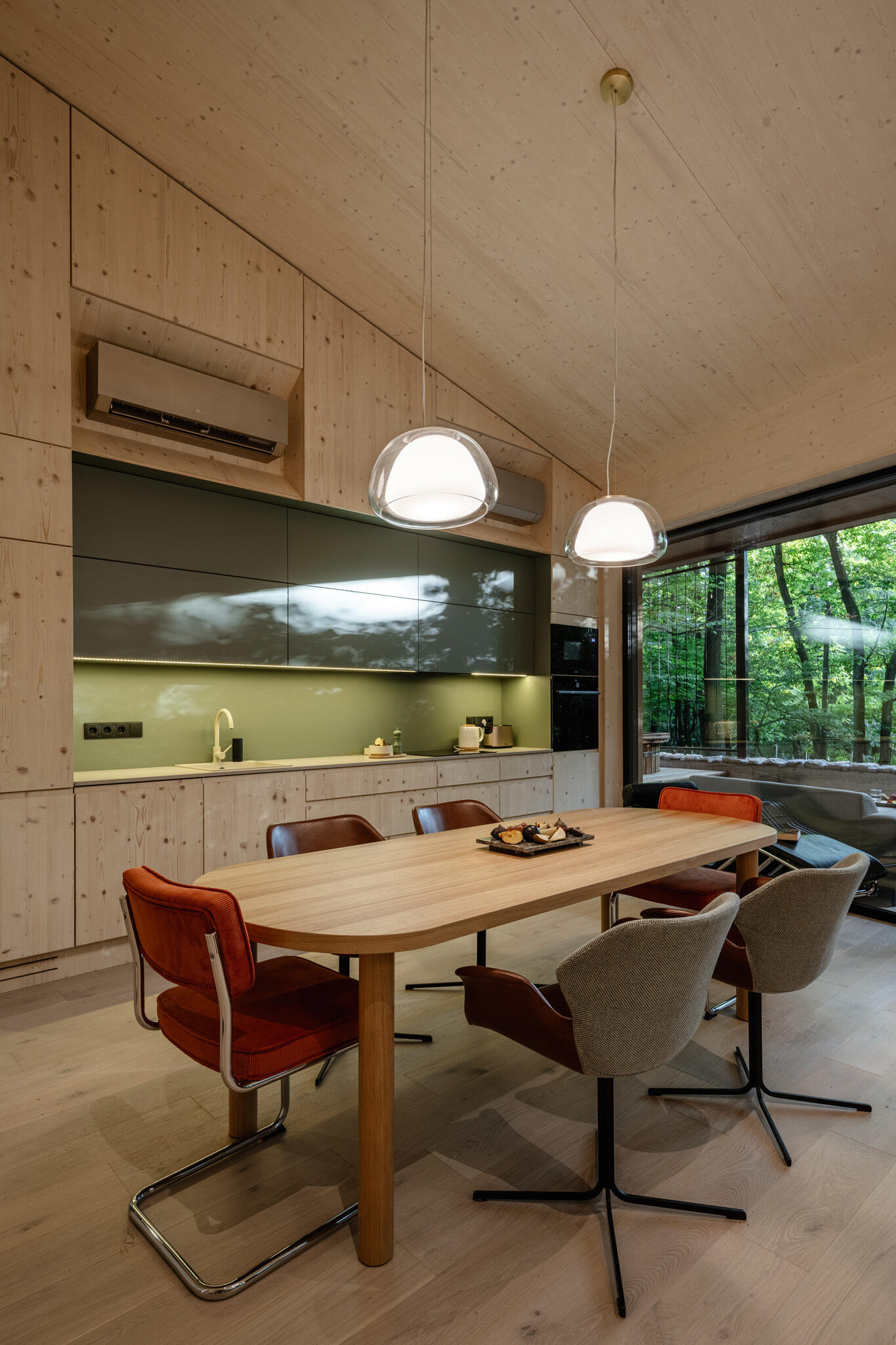 The kitchen, which lines the wall, continues the home’s restrained material palette. Exposed CLT surfaces remain visible, reinforcing the house’s construction logic.