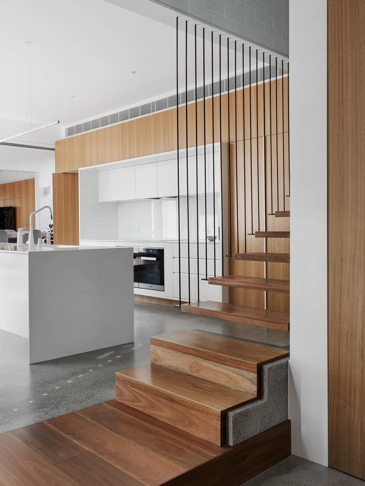 Concrete, steel, and wood stairs lead to the upper floor, transitioning from open treads to being part of a white-painted brick wall.