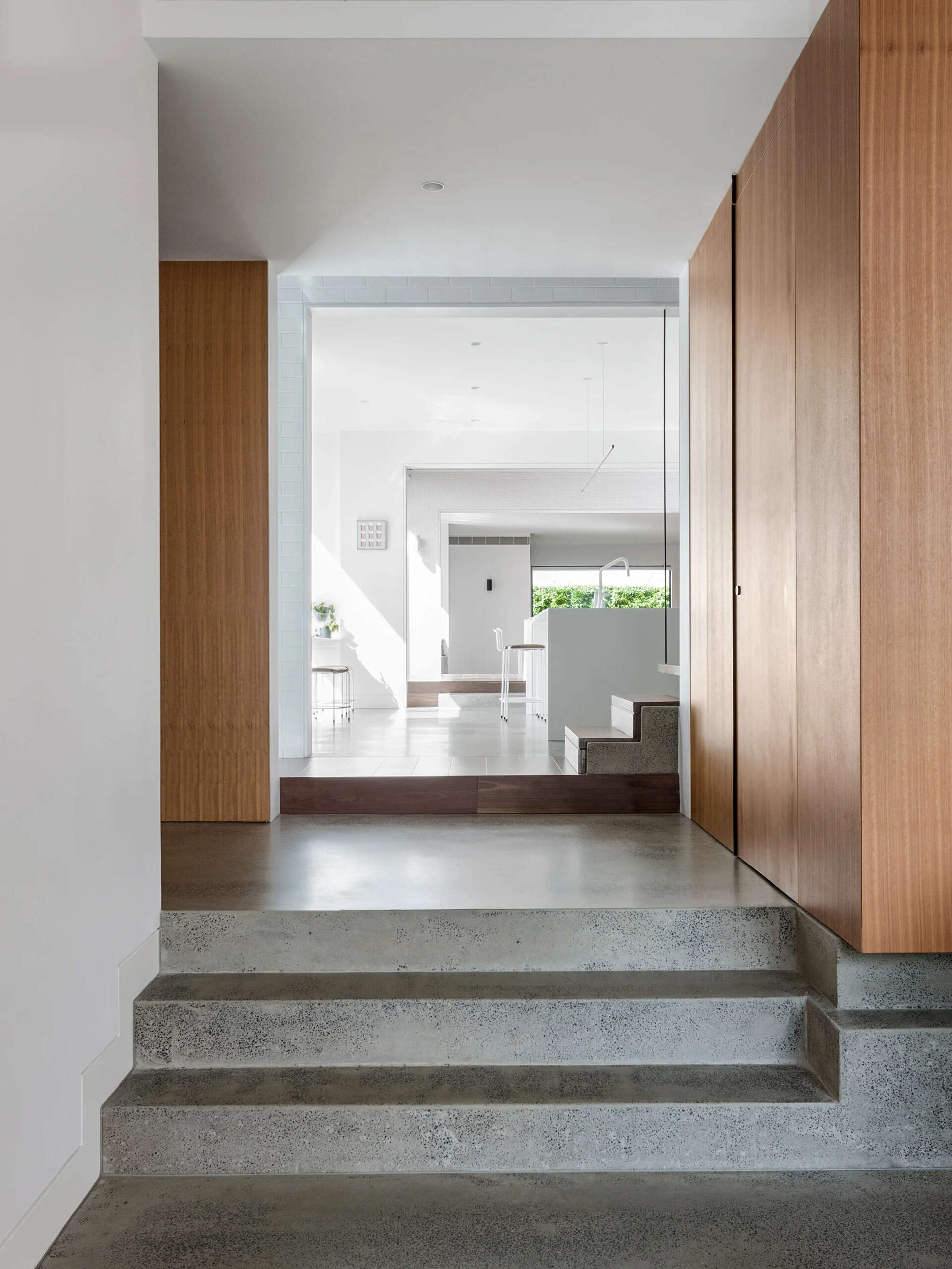 Bright, natural interiors with polished concrete floors, white walls, and wood accents create a modern and welcoming Melbourne home.