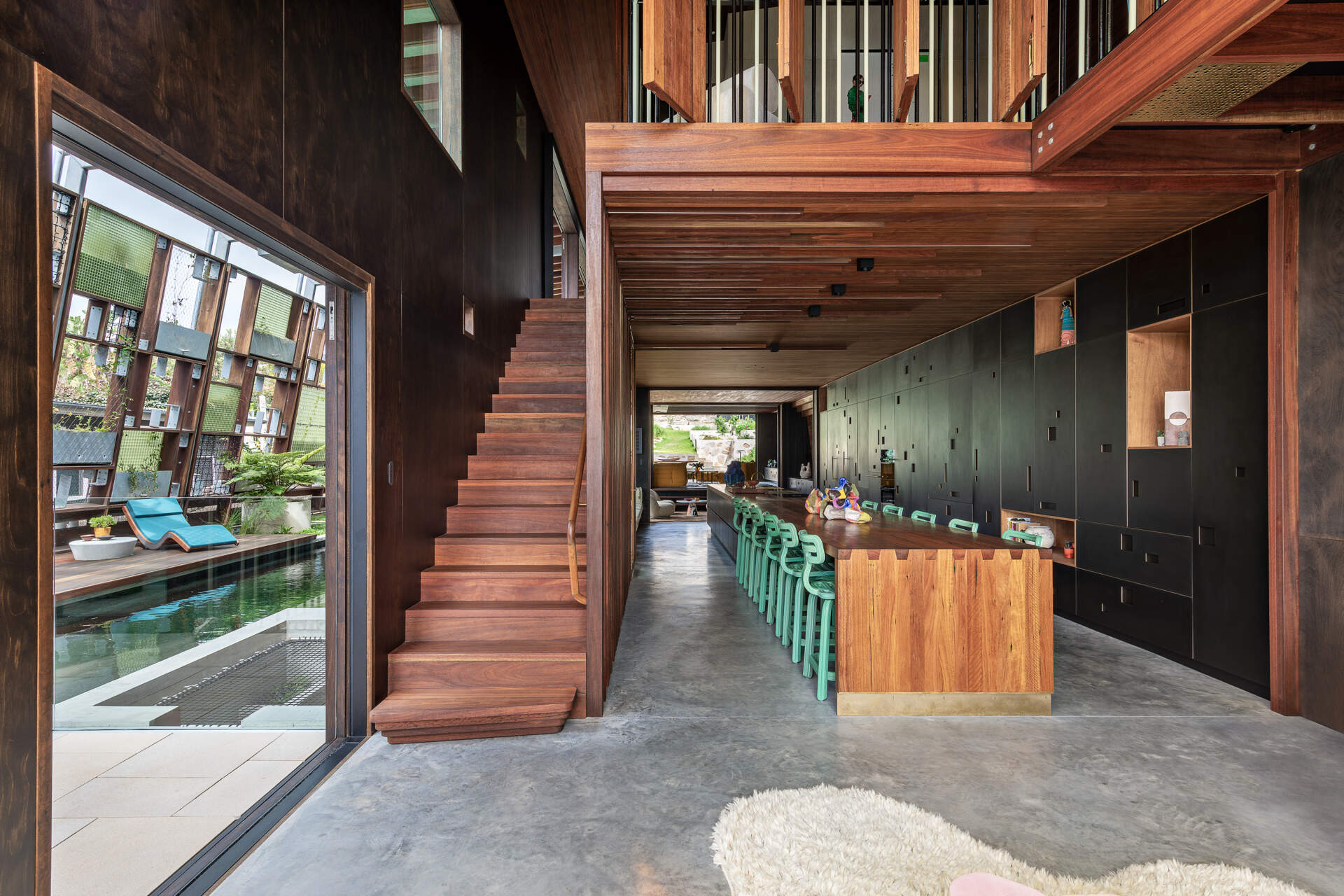 Nearby, the expansive dining space connects directly with the kitchen. Dappled light and airflow move through without barriers. 