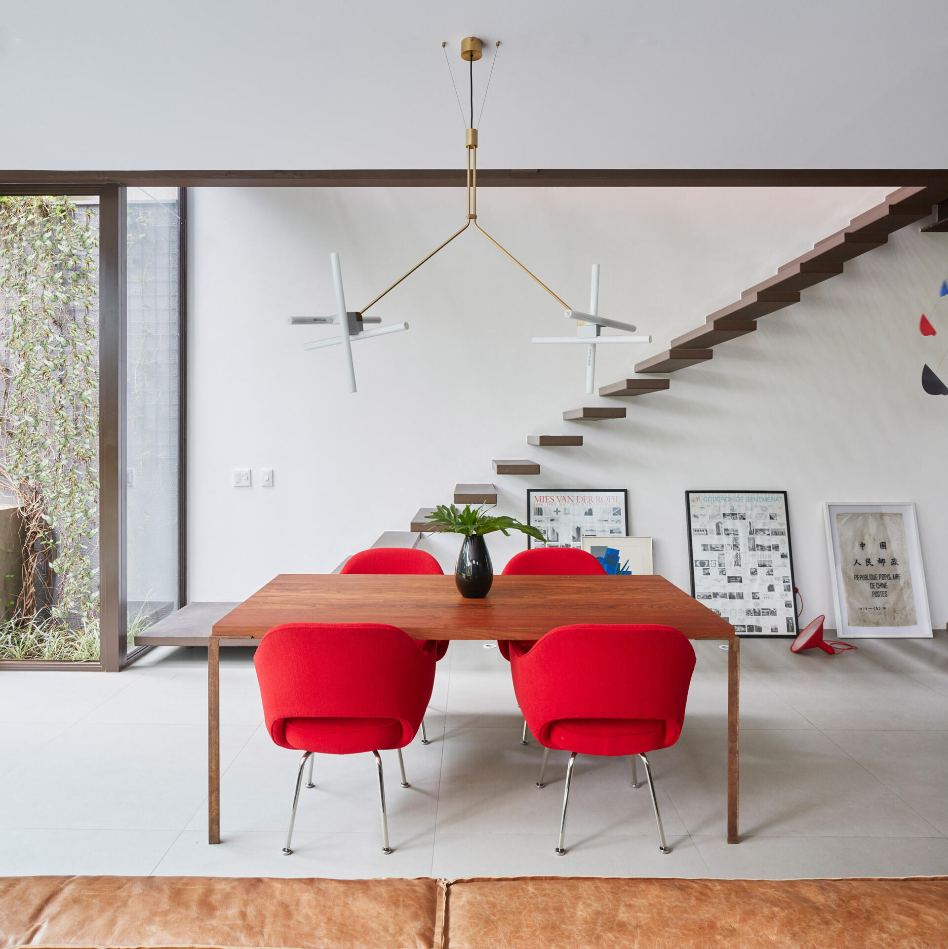 This dining area introduces a striking contrast. Bright red chairs bring an unexpected pop of color into the otherwise neutral interior, energizing the space and subtly defining the dining zone within the open plan layout.