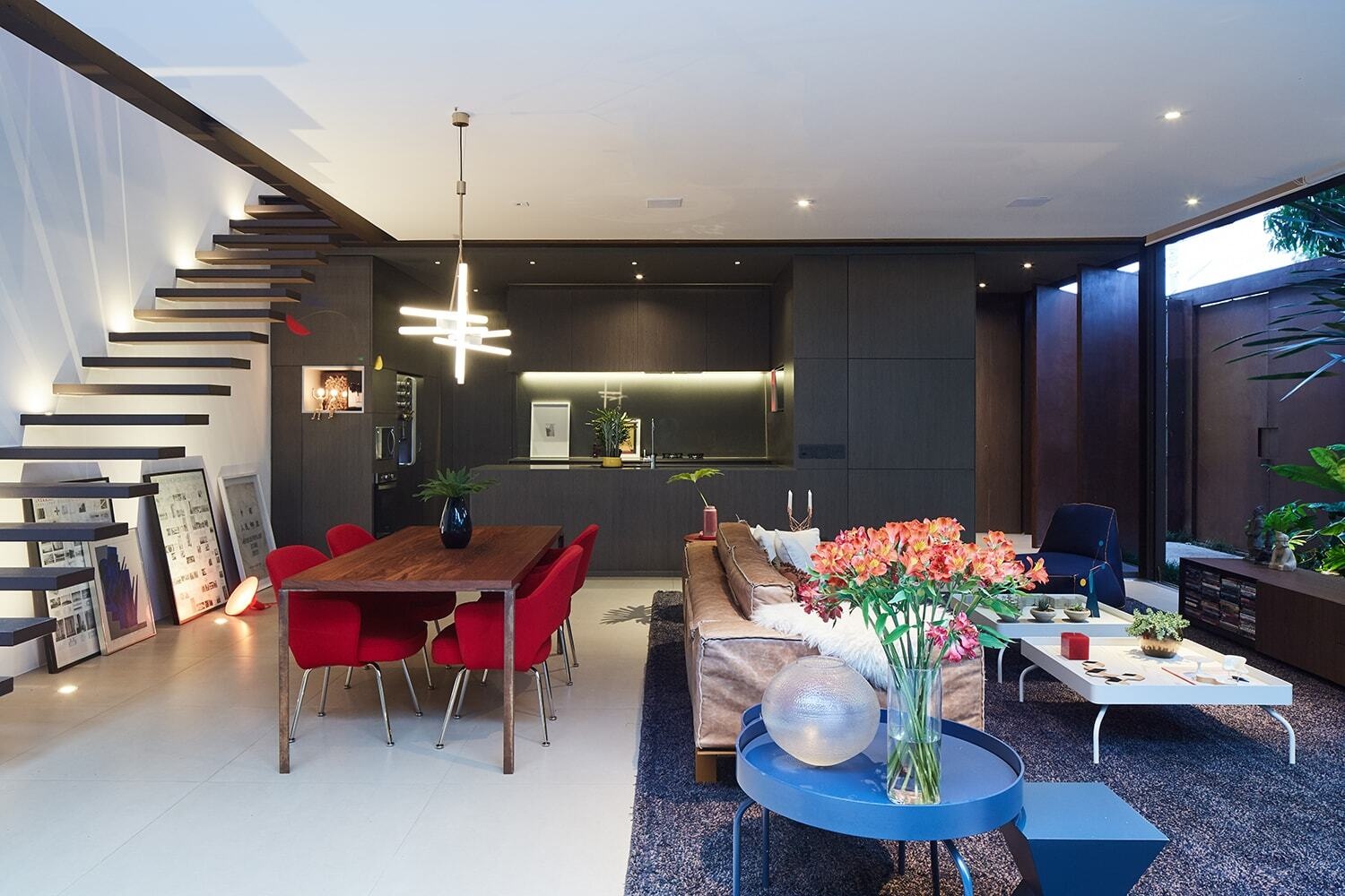 This dining area introduces a striking contrast. Bright red chairs bring an unexpected pop of color into the otherwise neutral interior, energizing the space and subtly defining the dining zone within the open plan layout.