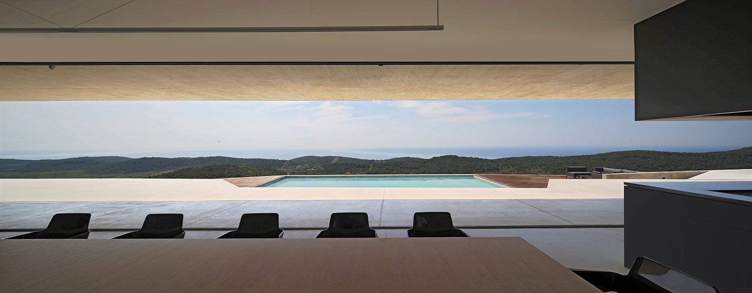 La cocina abierta y el comedor se conectan directamente con la terraza cuesta abajo y la terraza de la piscina.
