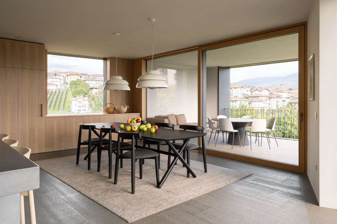 The dining space opens to a loggia overlooking the valley, blending interior comfort with expansive orchard views.