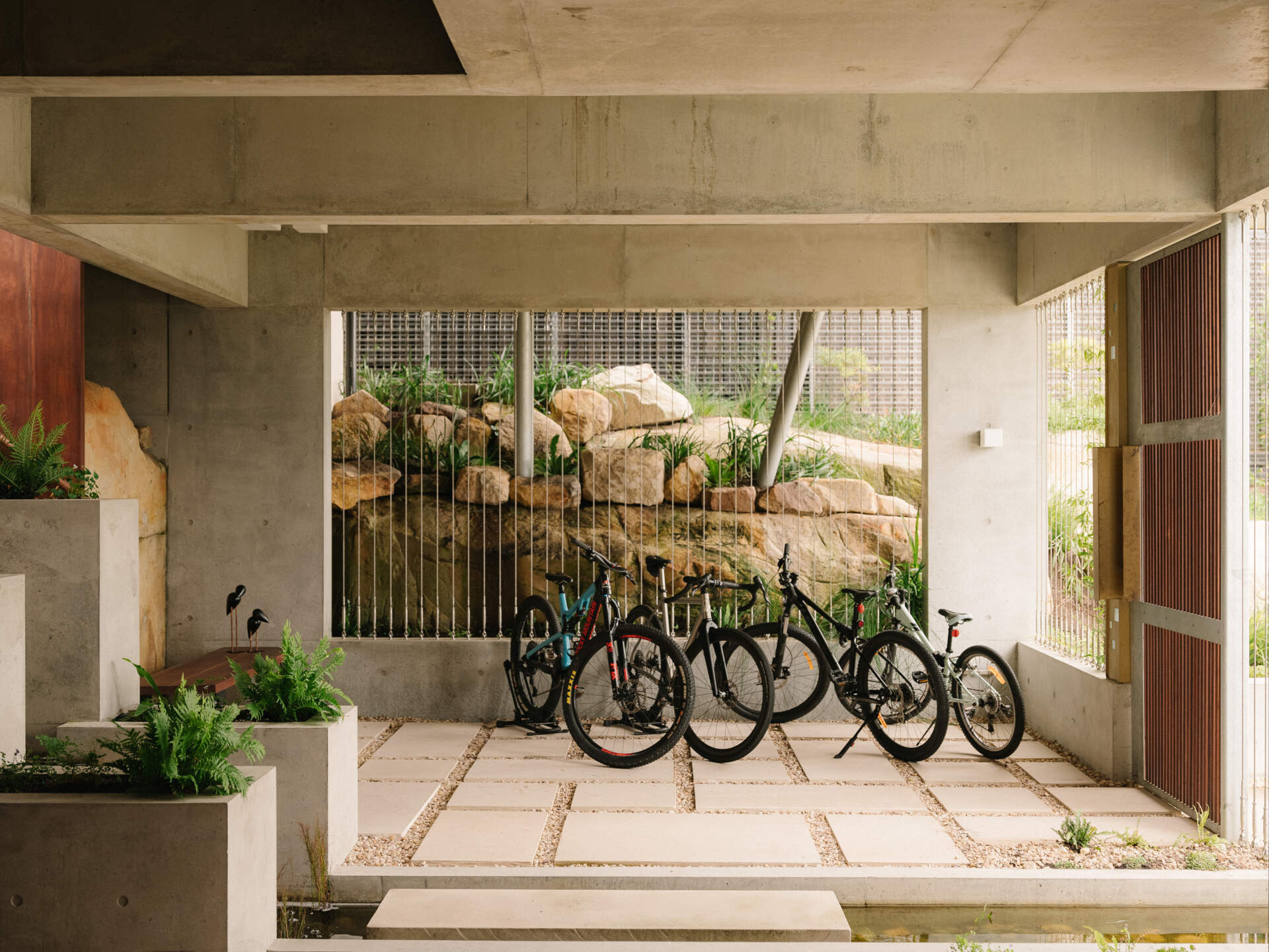 Cross a pond, step on stones, and ascend alongside a cascading waterfall to enter the living spaces.