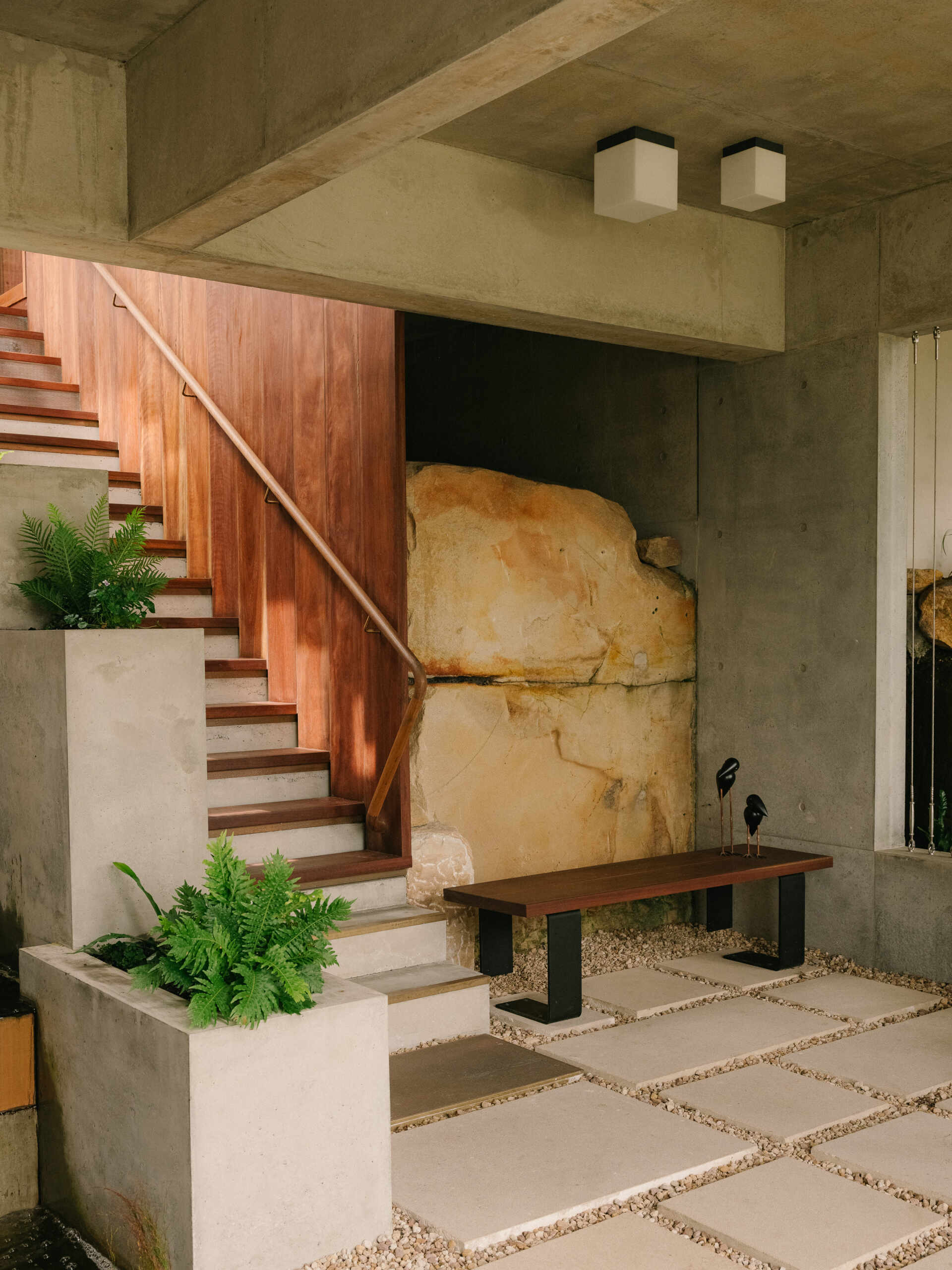 Cross a pond, step on stones, and ascend alongside a cascading waterfall to enter the living spaces.