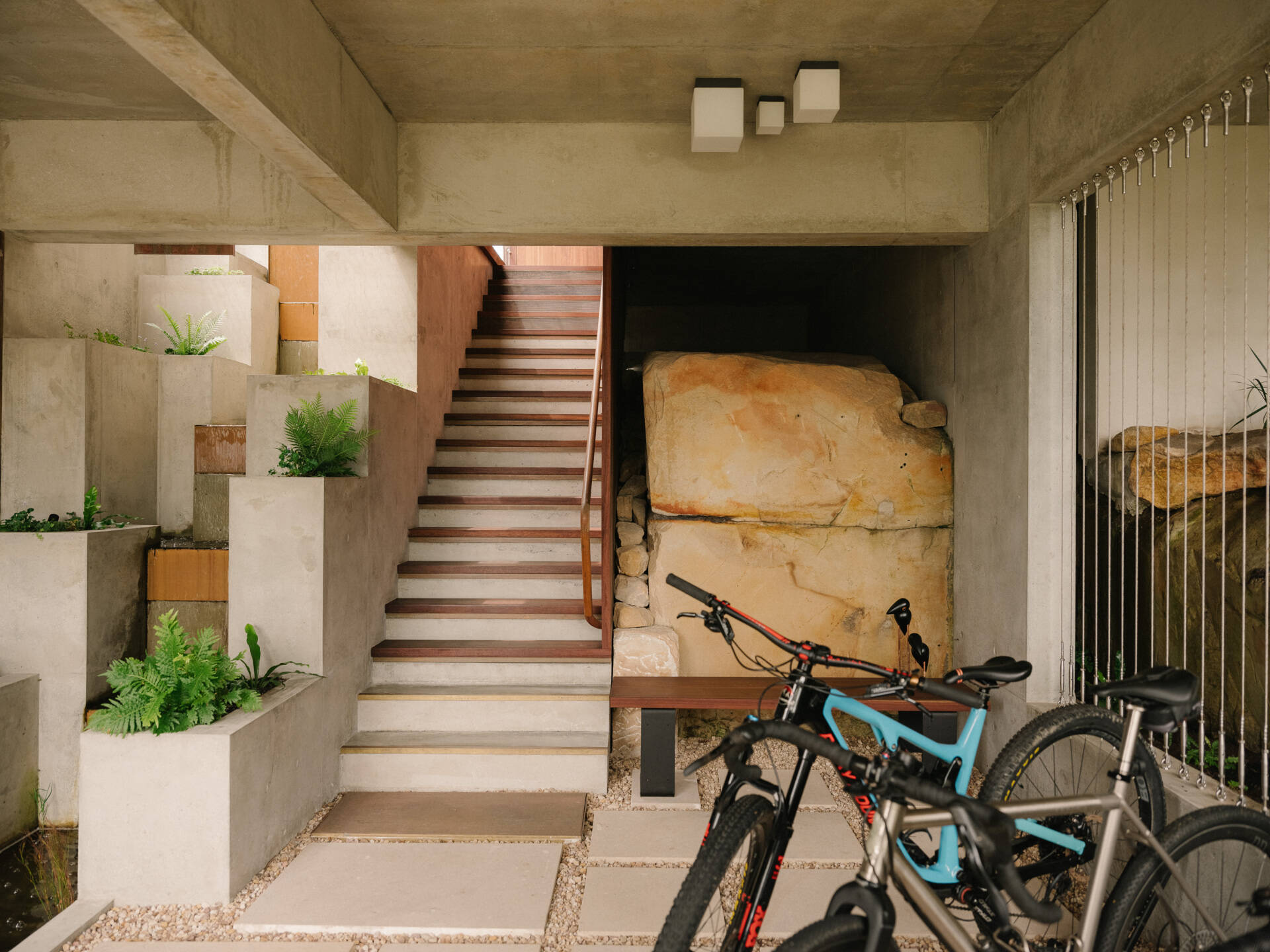 Cross a pond, step on stones, and ascend alongside a cascading waterfall to enter the living spaces.