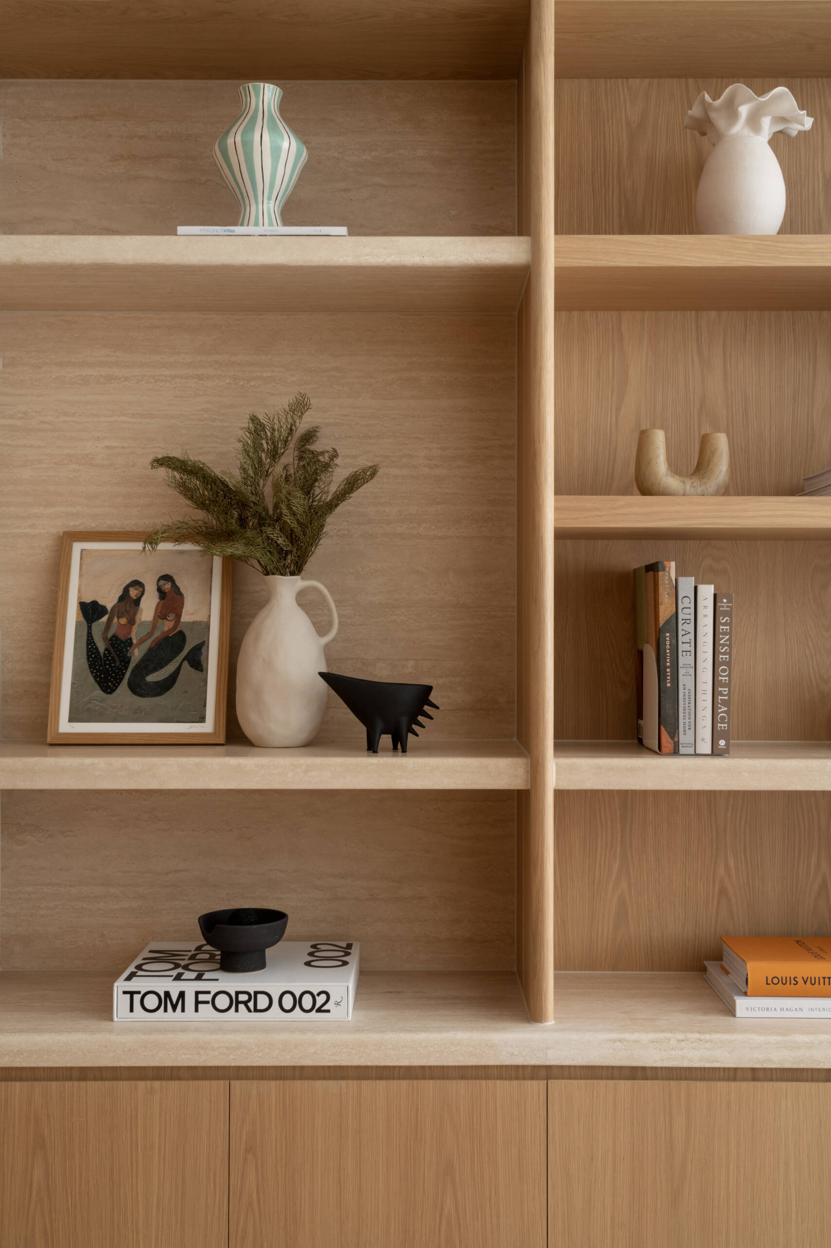 A sophisticated home office with custom oak doors, curved shelving, a travertine threshold, and soft Venetian-plaster light.