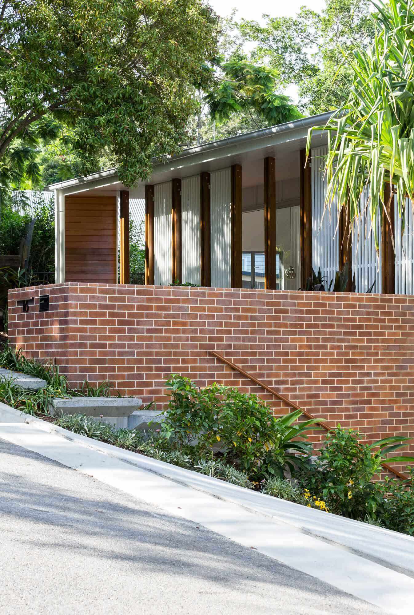 A mid-century inspired home with brick wall, wood, and white facade.