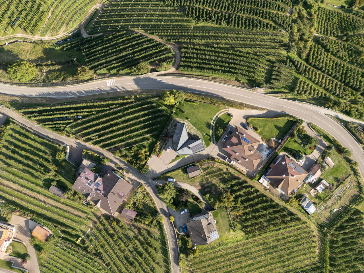 Black larch wood cladding gives this Italian hillside home a striking presence among apple orchards while staying rooted in local tradition.