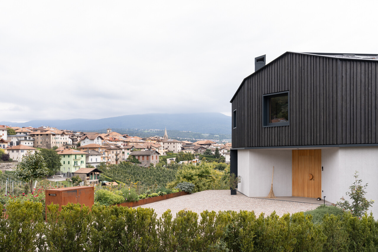 Black larch wood cladding gives this Italian hillside home a striking presence among apple orchards while staying rooted in local tradition.