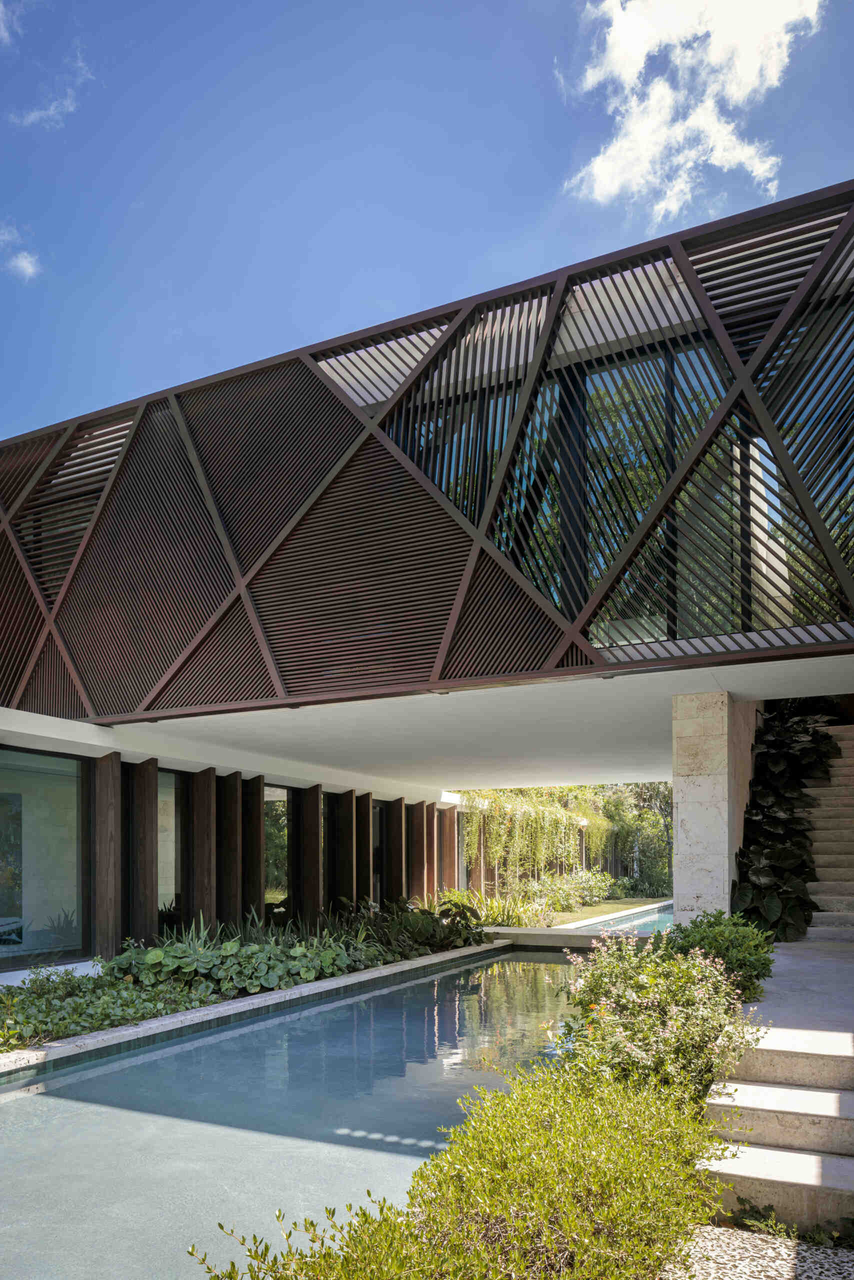 Wood panels and louvers wrap the upper level, providing sun control while introducing natural texture to the exterior.