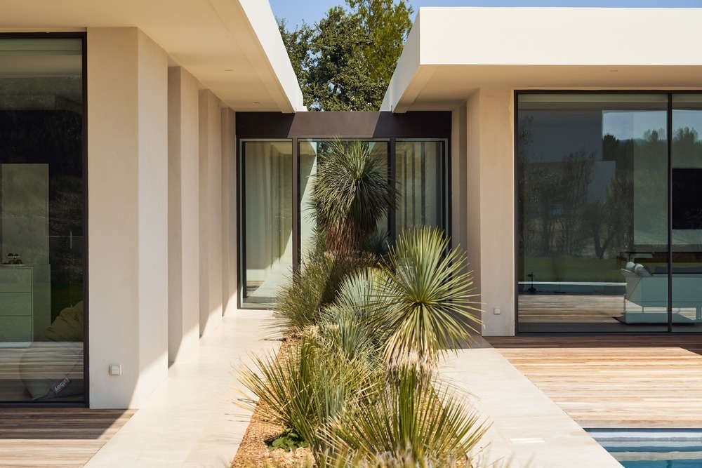 Landscaping runs between all three buildings, visually linking garage, kitchen, living spaces and bedrooms.