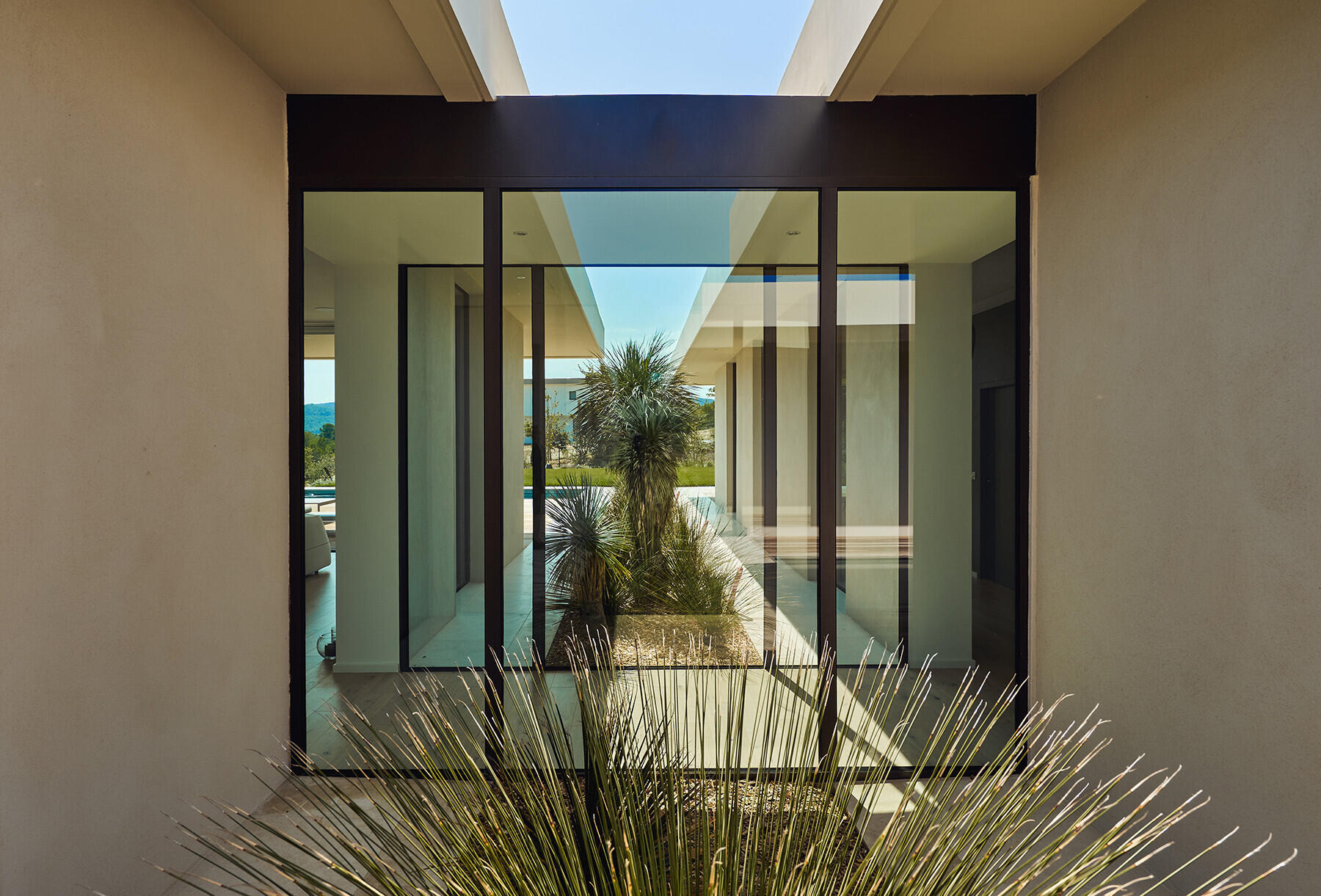 A floor to ceiling glass corridor connects the buildings, turning a simple hallway into a garden viewing experience.