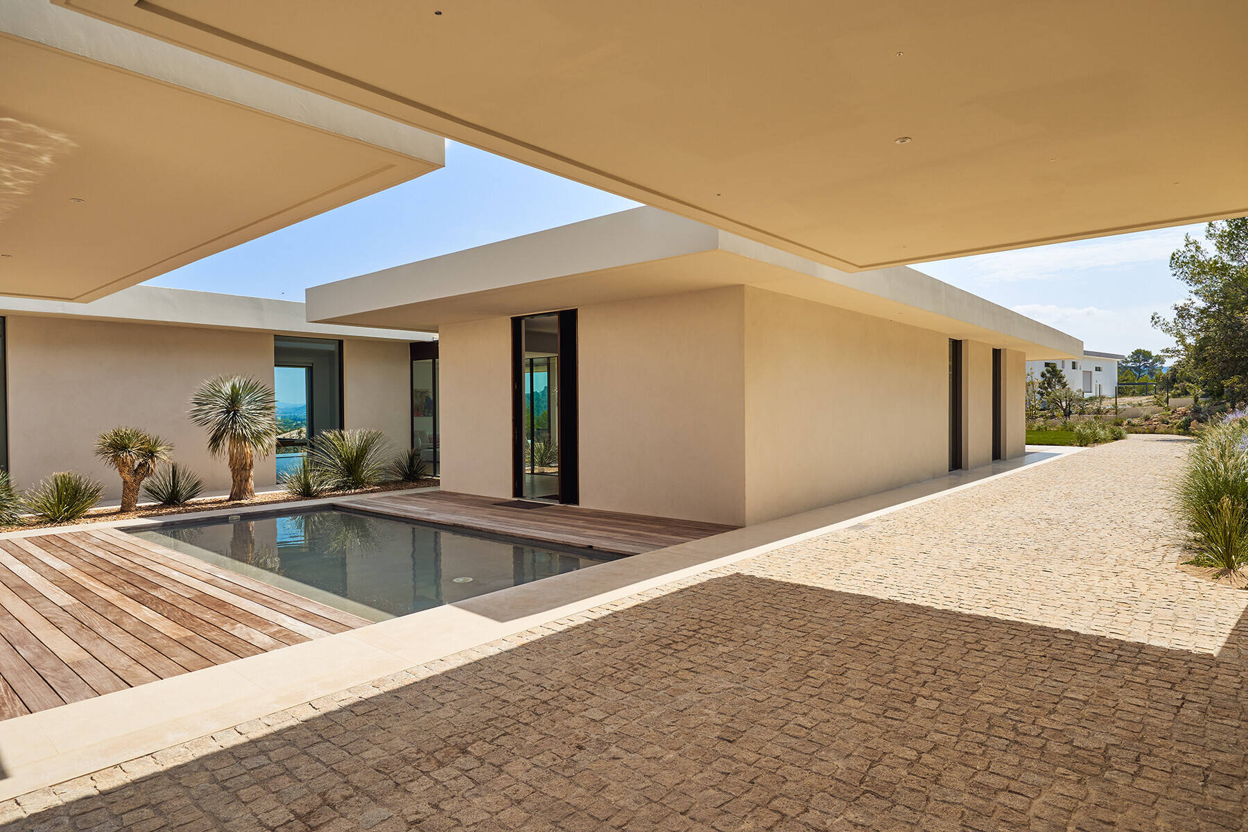 A reflective water feature and linear garden strip soften the entrance and introduce nature as a central design element.