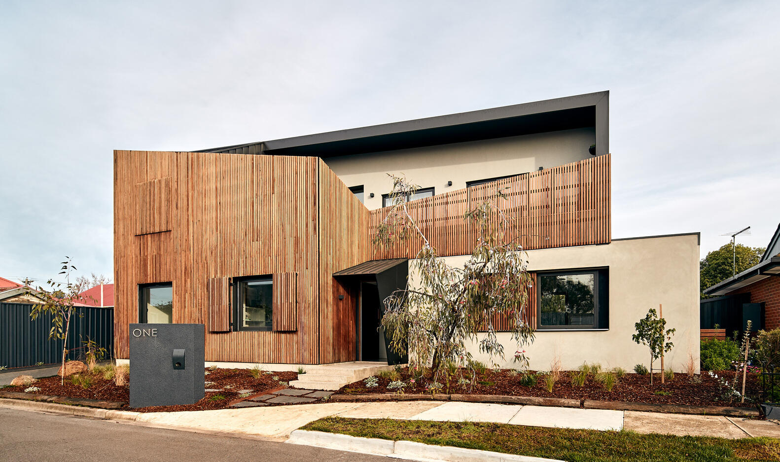 A modern Melbourne home uses a timber screen to soften its facade and blend into a quiet suburban cul-de-sac.