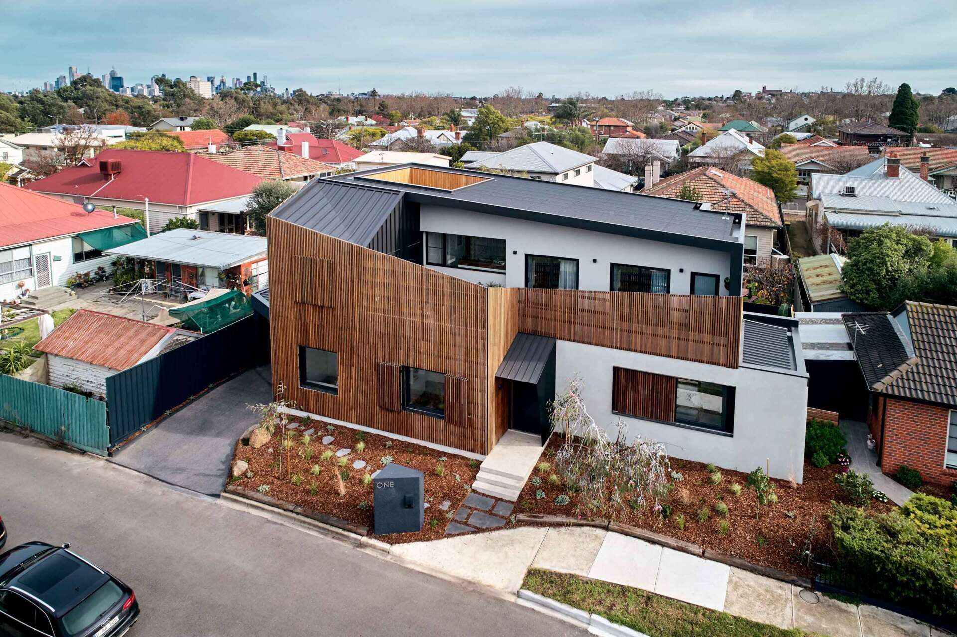 A modern Melbourne home uses a timber screen to soften its facade and blend into a quiet suburban cul-de-sac.