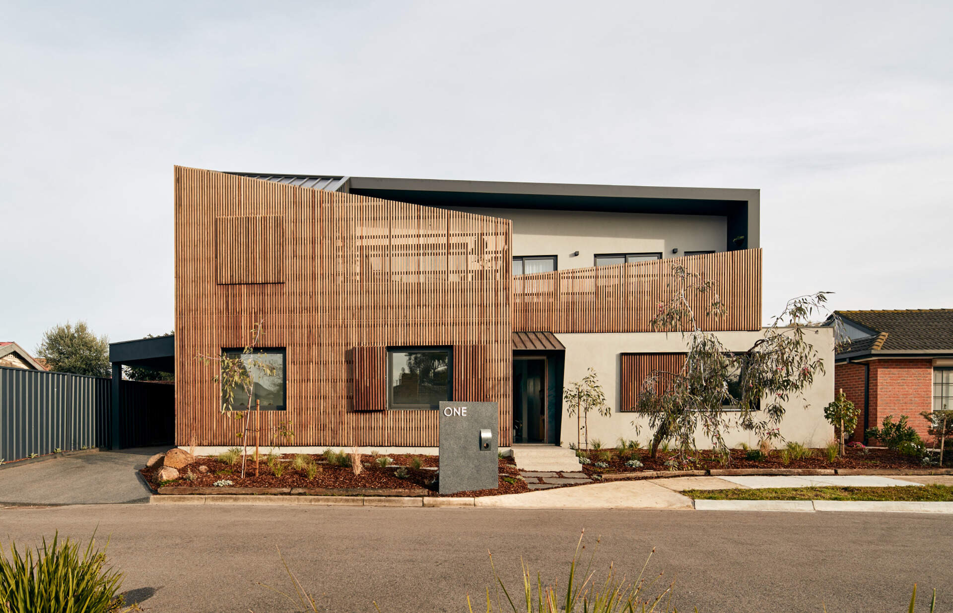 A modern Melbourne home uses a timber screen to soften its facade and blend into a quiet suburban cul-de-sac.