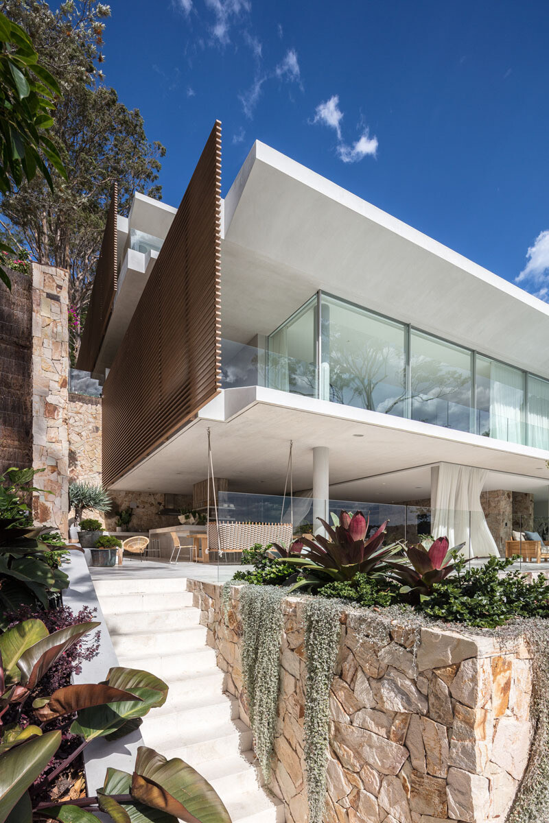 Terraced concrete slabs and cascading levels are fully visible from the pool, highlighting the home’s floating design and connection to the slope.