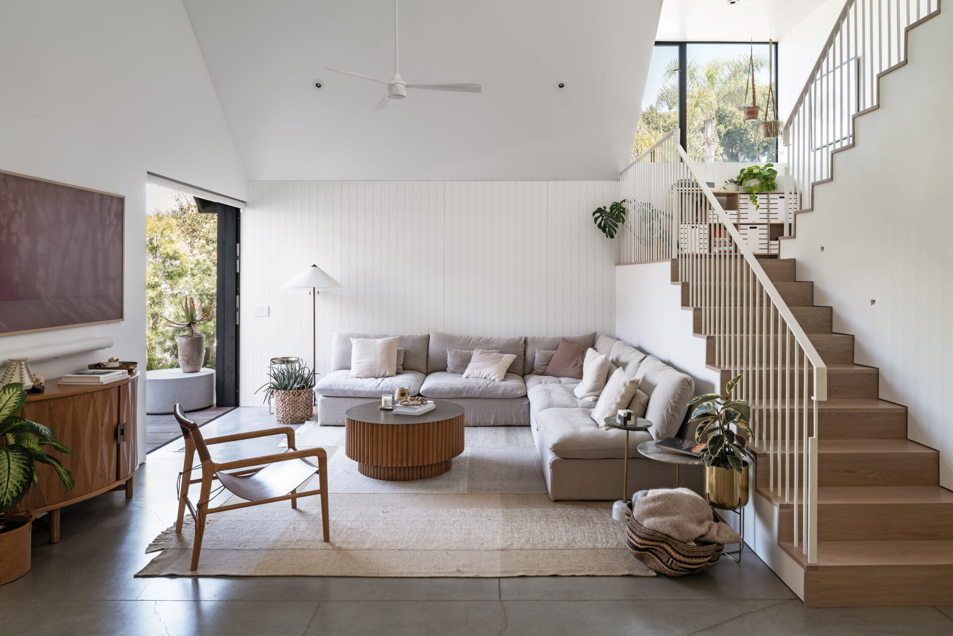 The living room occupies the ground floor alongside other shared spaces. From here, the house spills directly into the backyard and patio, extending daily life outdoors.