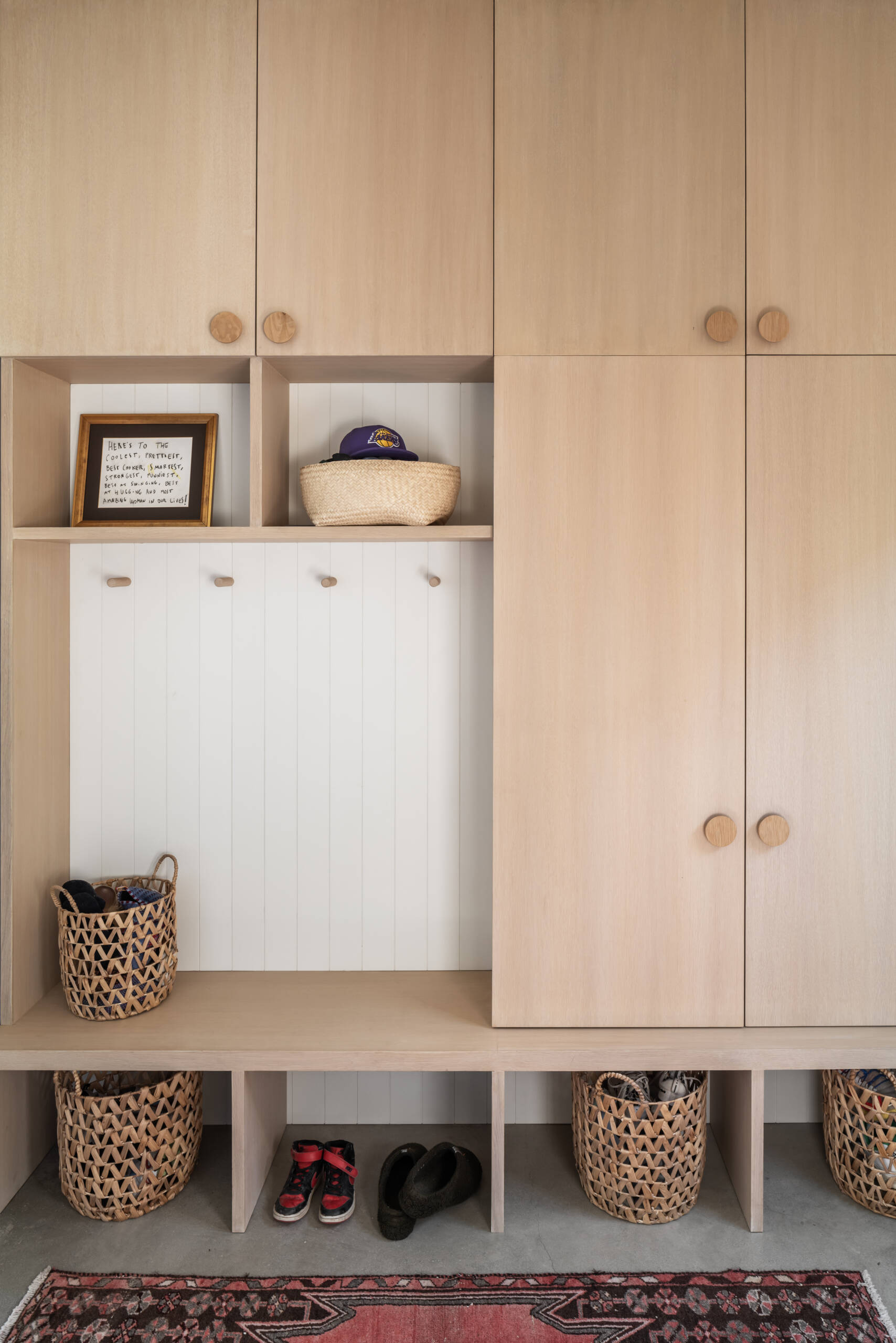 The entry sequence sets the tone for the interior of this modern home. A dutch door and polished concrete floors ground the space, while white oak and white painted grooved paneling in the adjacent mudroom add warmth and texture. The materials feel durable and intentional, designed for a family of four rather than a showpiece home.