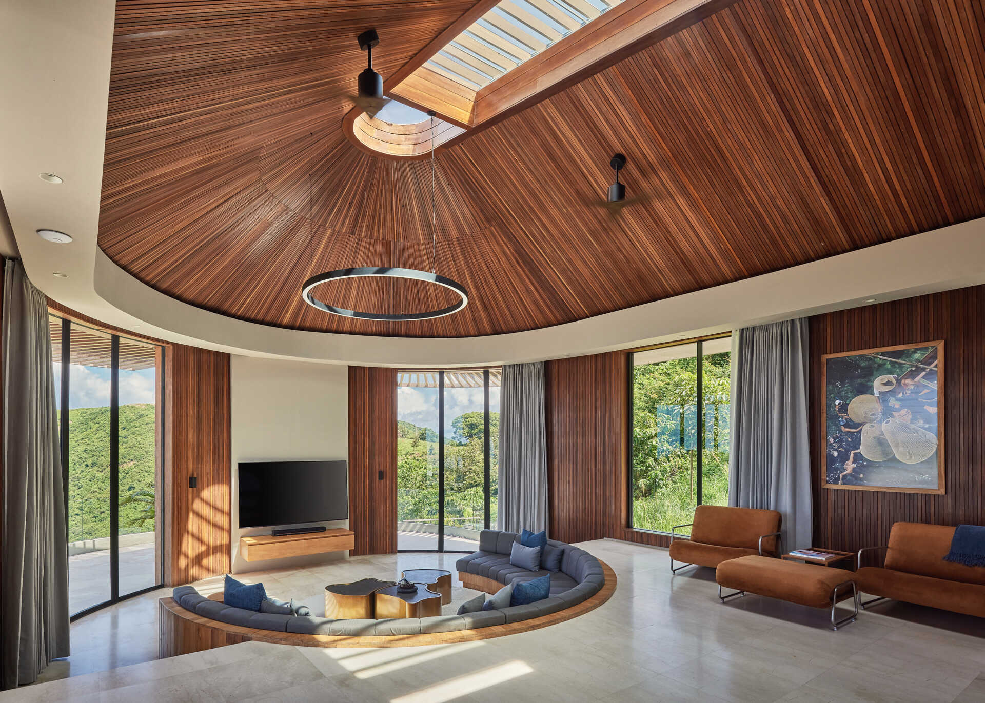 Curved built-in seating continues the home’s circular language, turning the TV room into an architectural feature.